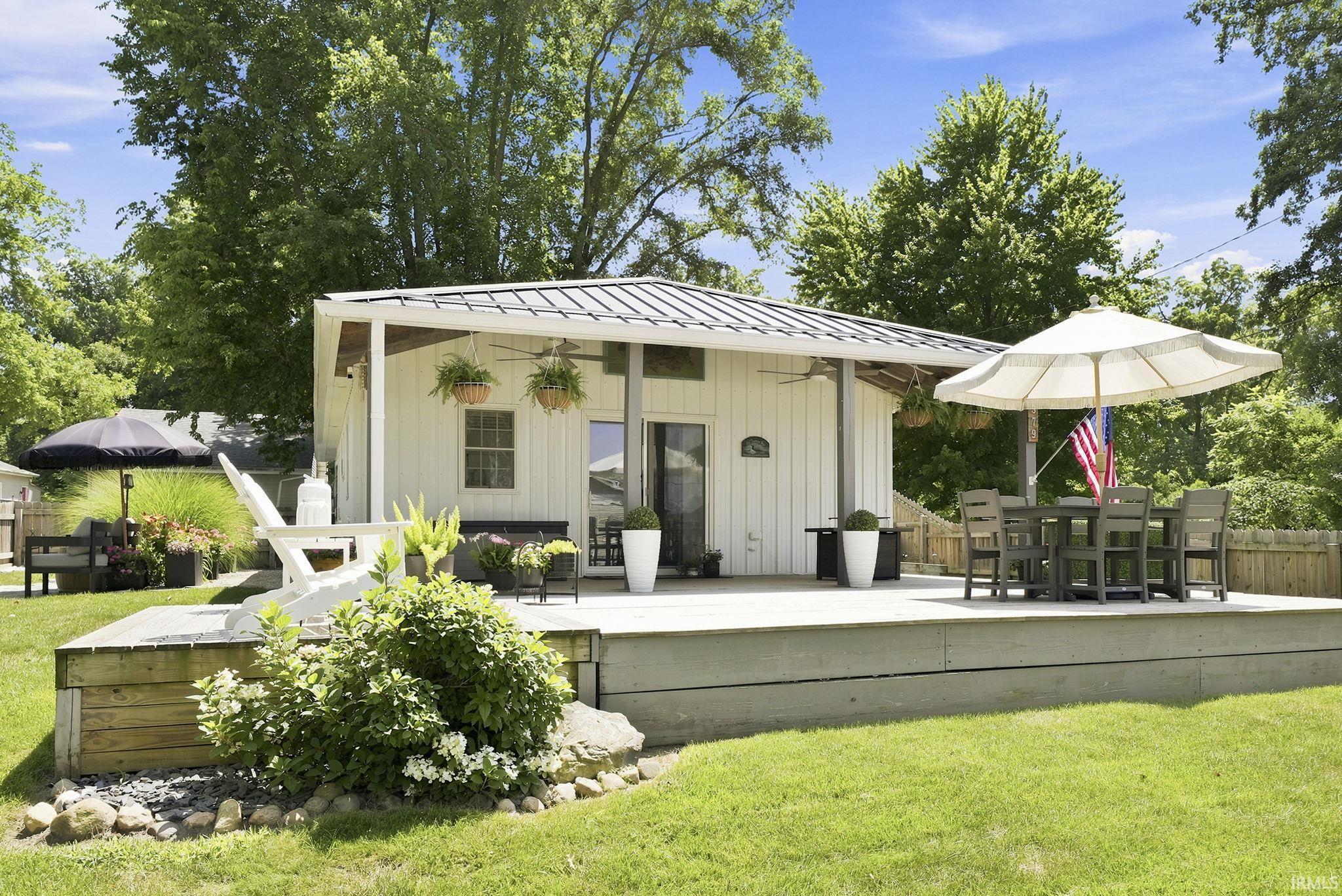 Image 0: Spacious outdoor deck with a private yard, covered patio, metal roof, and white board and batten siding, Back Of Structure Image 0: Spacious outdoor deck with a private yard, covered patio, metal roof, and white board and batten siding, Back Of Structure