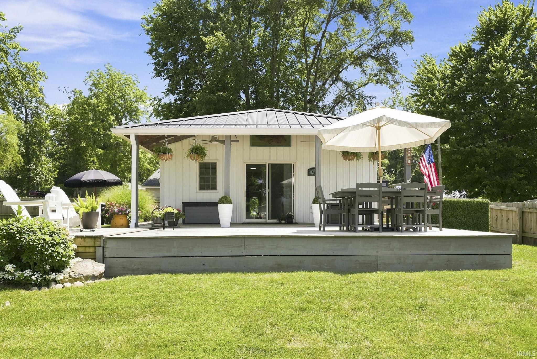 Image 2: White horizontal siding exterior featuring a metal roof and an expansive wood-finish deck, Back Of Structure Image 2: White horizontal siding exterior featuring a metal roof and an expansive wood-finish deck, Back Of Structure