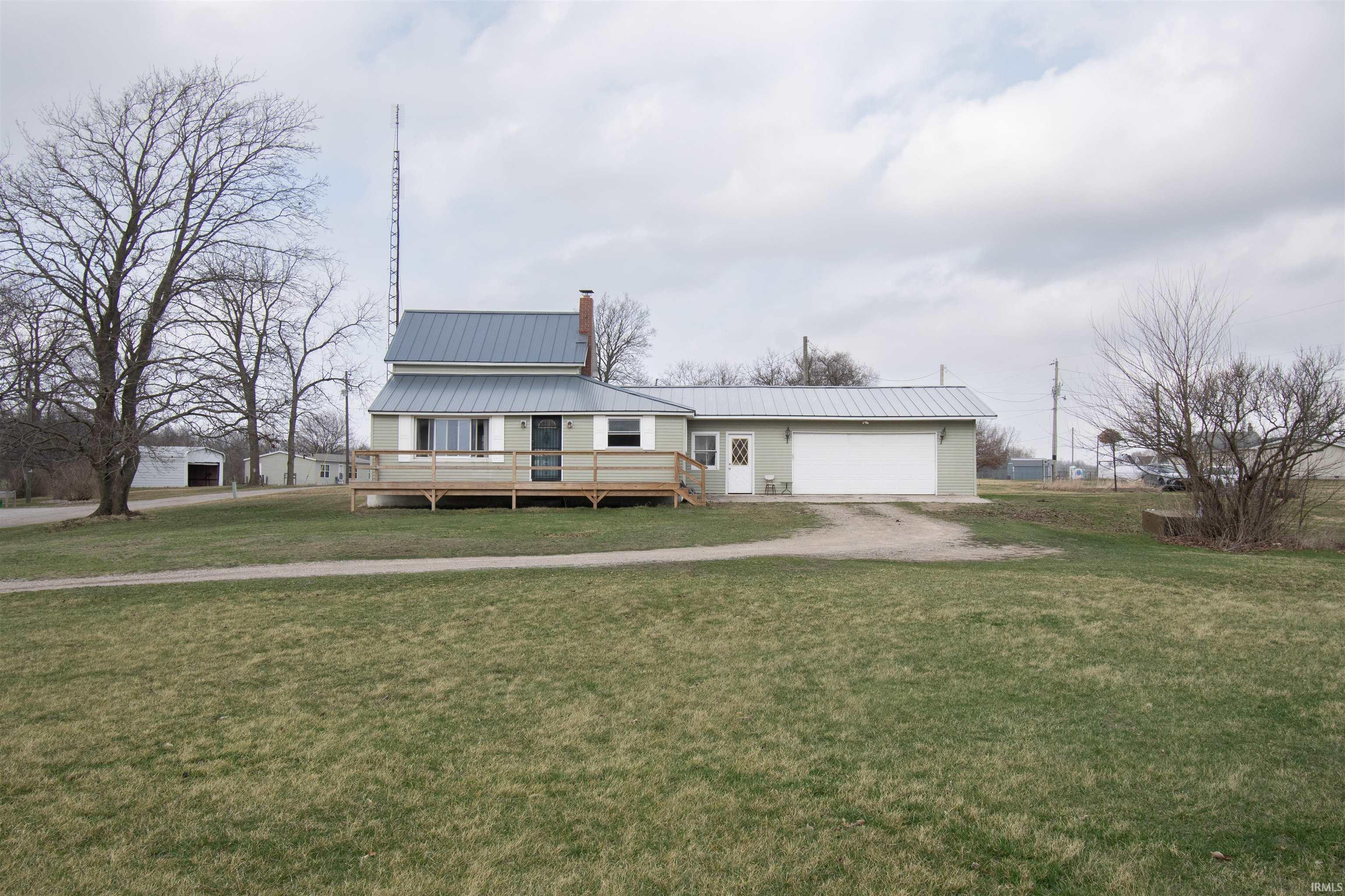 Image 0: View of front of house featuring a metal roof, a wooden deck, a front lawn, a chimney, and driveway, Front Of Structure