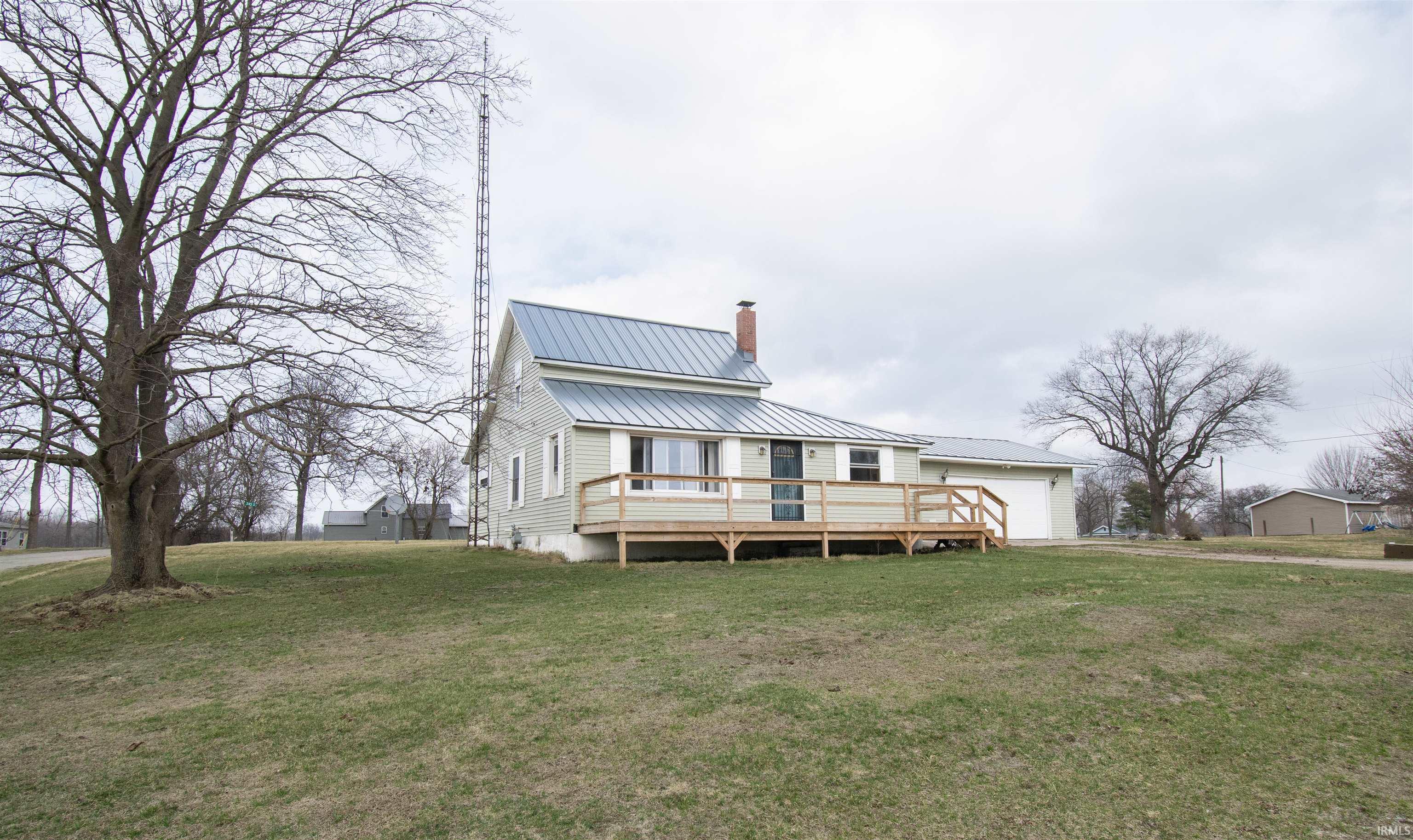 Image 1: View of front of house with a metal roof, a chimney, a front lawn, a wooden deck, and a garage, Front Of Structure