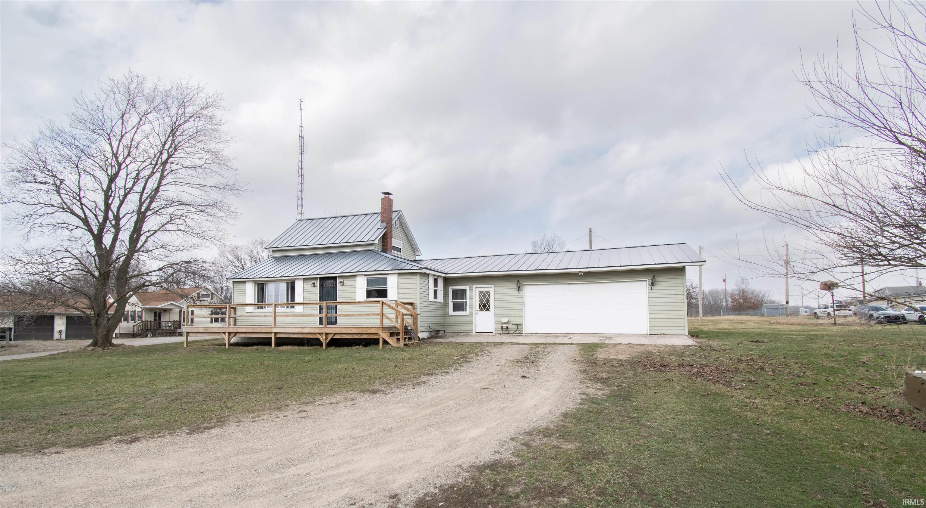 Image 2: View of front of home featuring a front lawn, a metal roof, dirt driveway, and a wooden deck, Front Of Structure