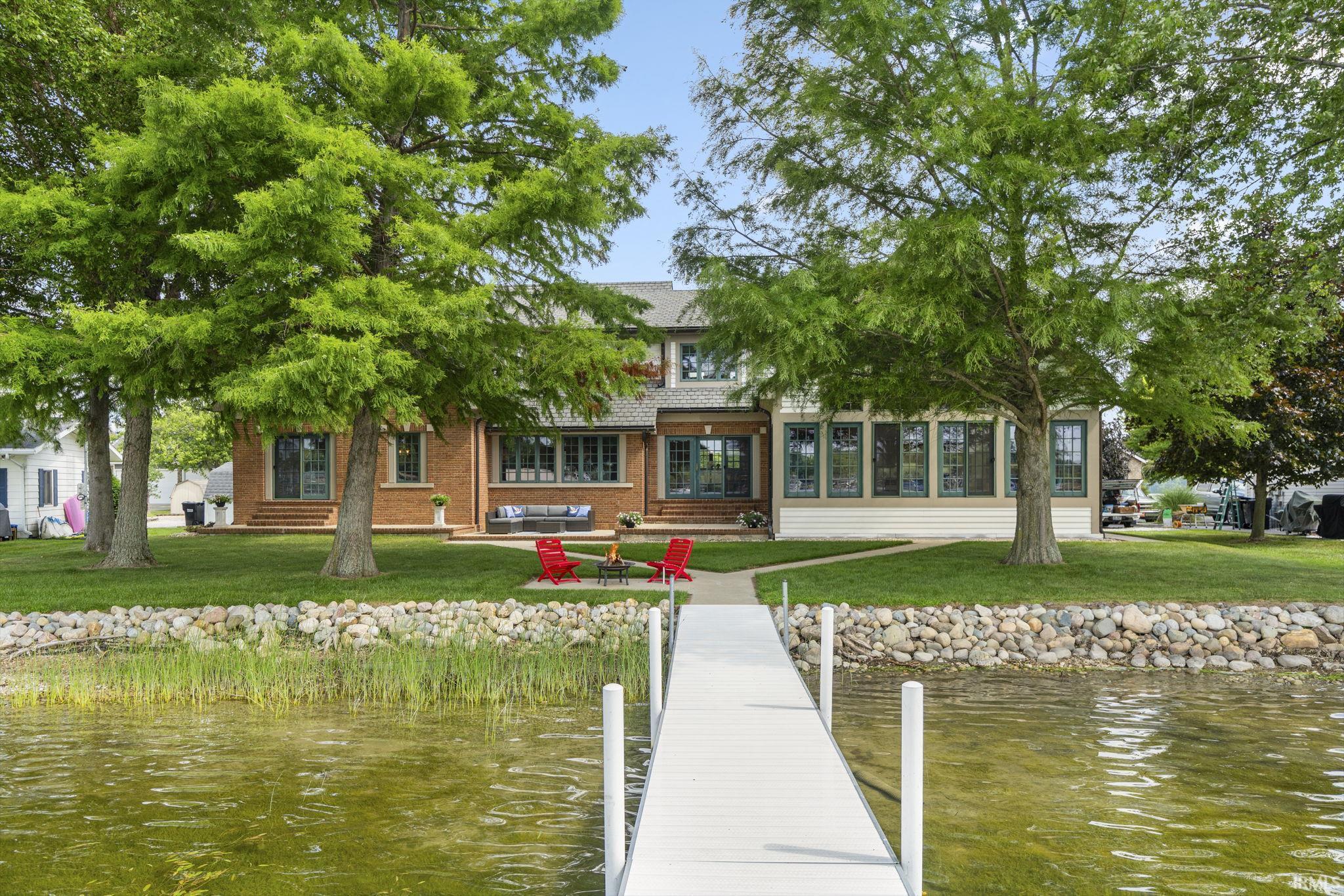 Image 0: Dock area with a water view, a lawn, and a sunroom, Dock