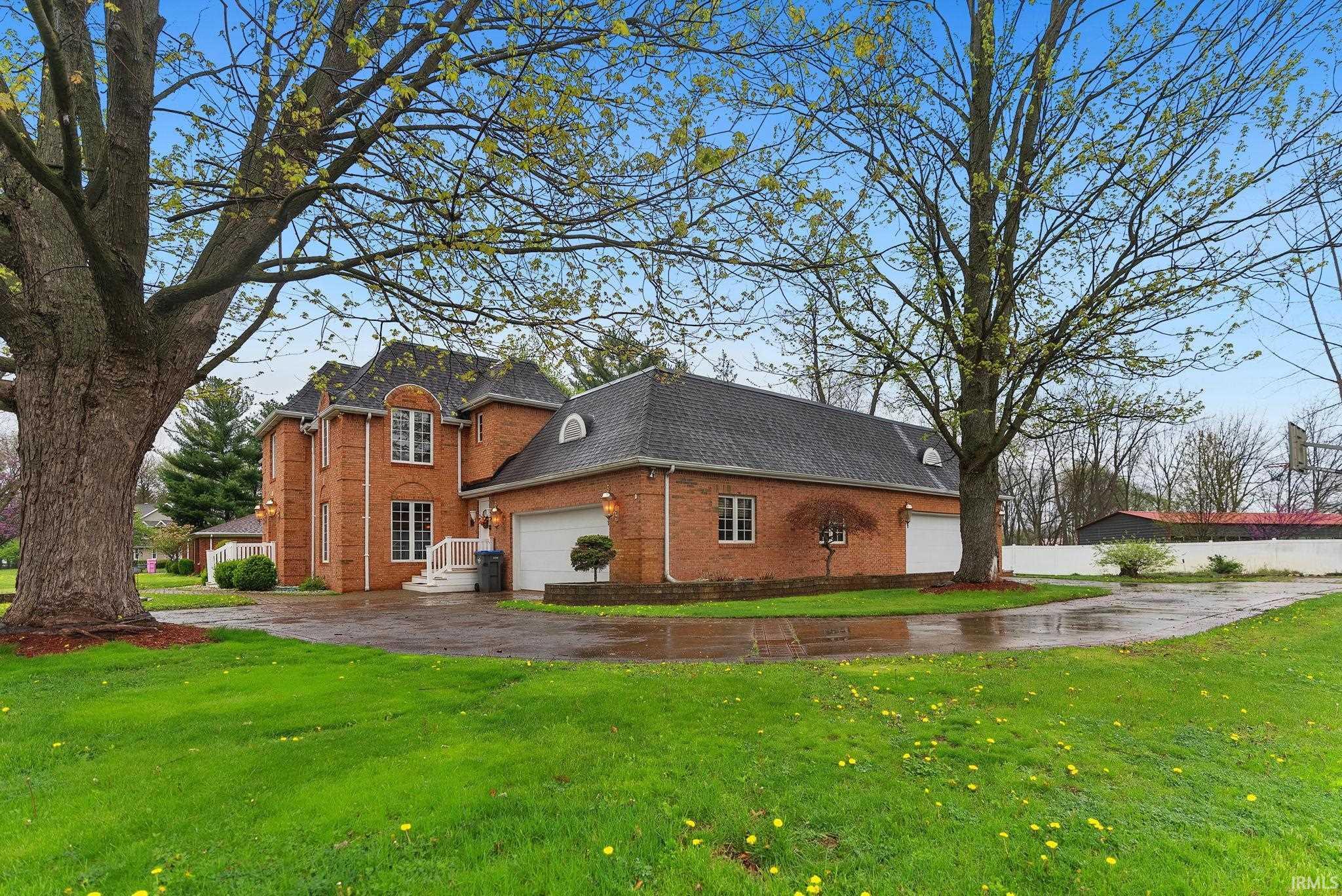 Image 2: View of property exterior with roof with shingles, brick siding, a yard, and asphalt driveway, Side Of Structure Image 2: View of property exterior with roof with shingles, brick siding, a yard, and asphalt driveway, Side Of Structure