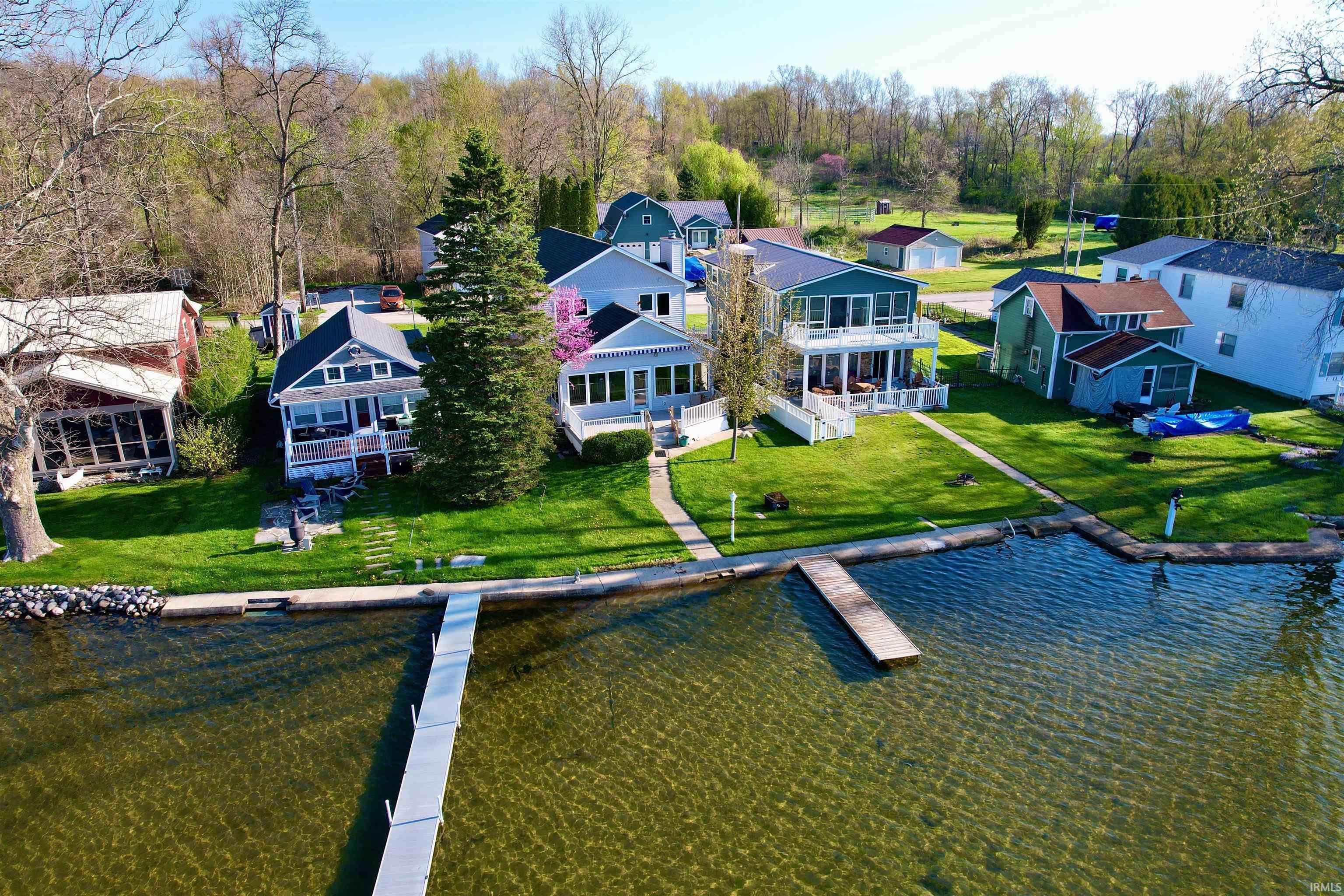 Image 0: Waterfront property featuring a private dock extending into the lake, a manicured lawn, and mature trees, Aerial View