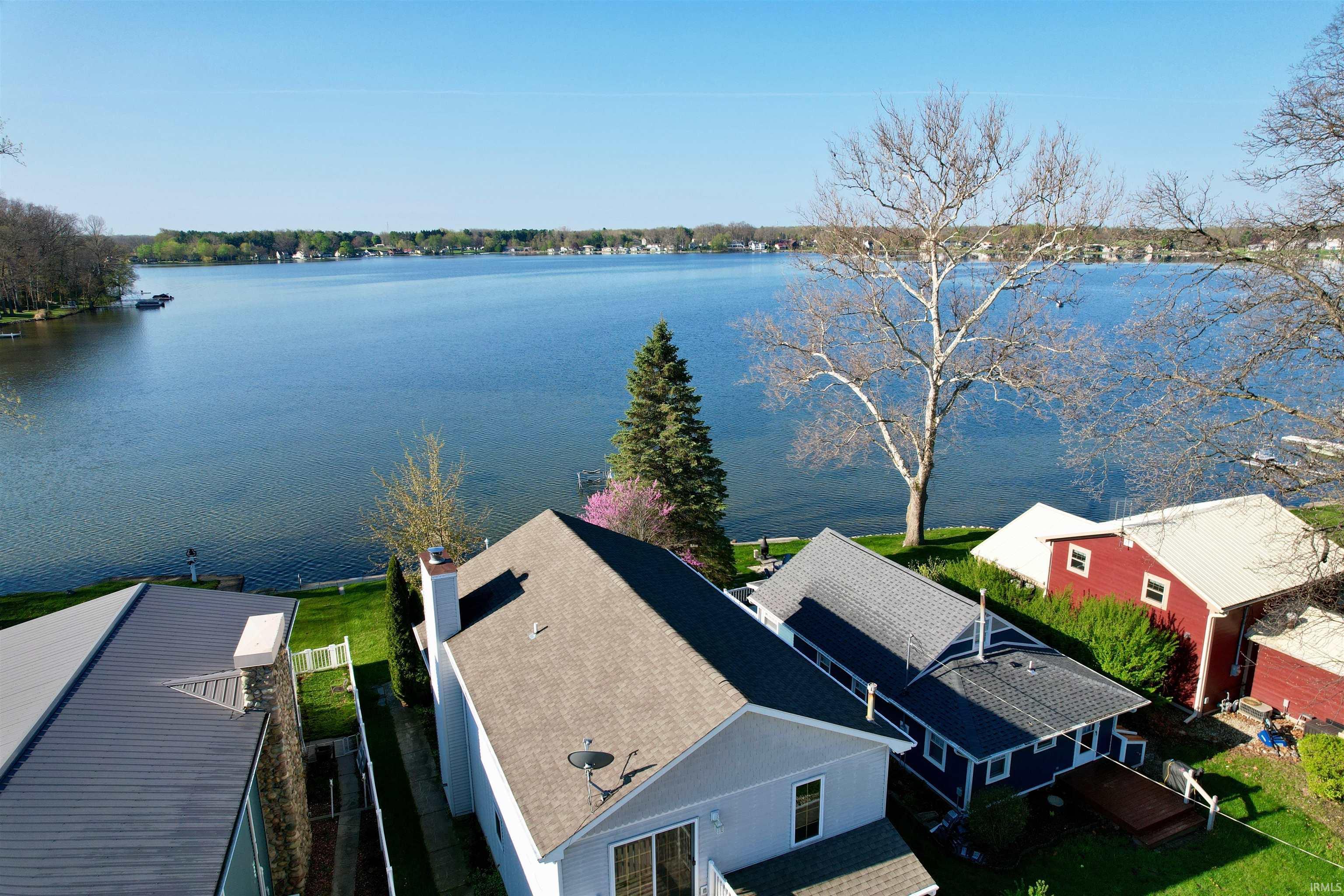 Image 3: Expansive waterfront property featuring a substantial body of water, green lawn, a large deciduous tree, and a notable evergreen tree, Aerial View