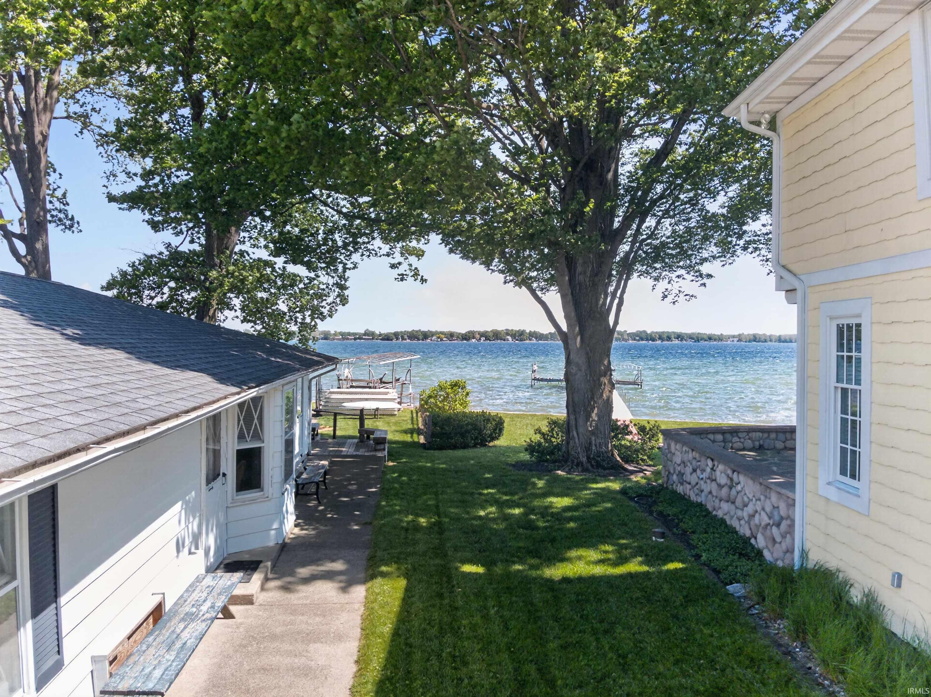 Image 1: Expansive waterfront property featuring a large lawn, mature trees, a private dock with a boat lift, and a stone retaining wall, Yard