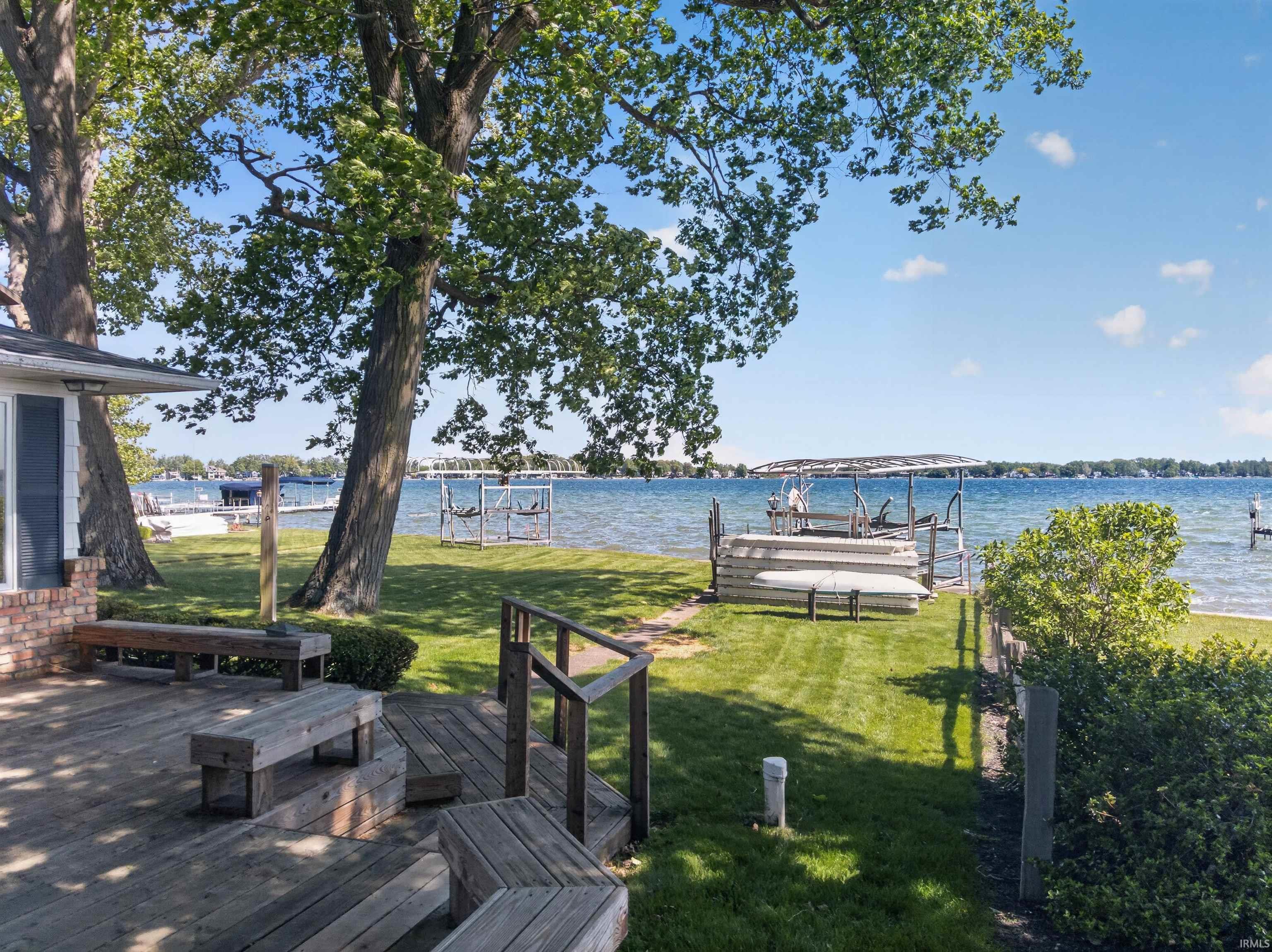 Image 2: Expansive waterfront property featuring a wooden deck, a manicured lawn, mature trees, and a private boat lift, Yard