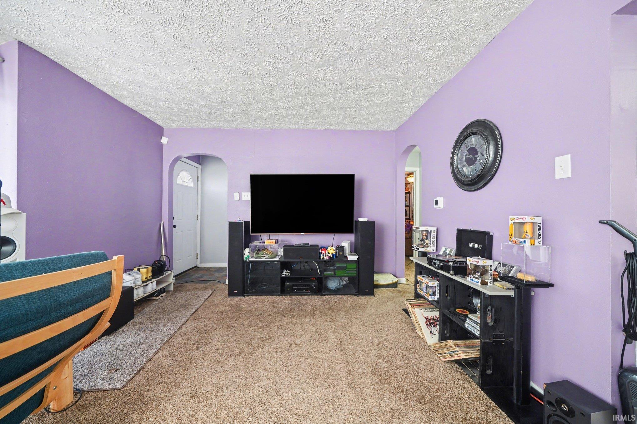 Image 1: Living area featuring arched walkways, light colored carpet, and a textured ceiling, Living Room