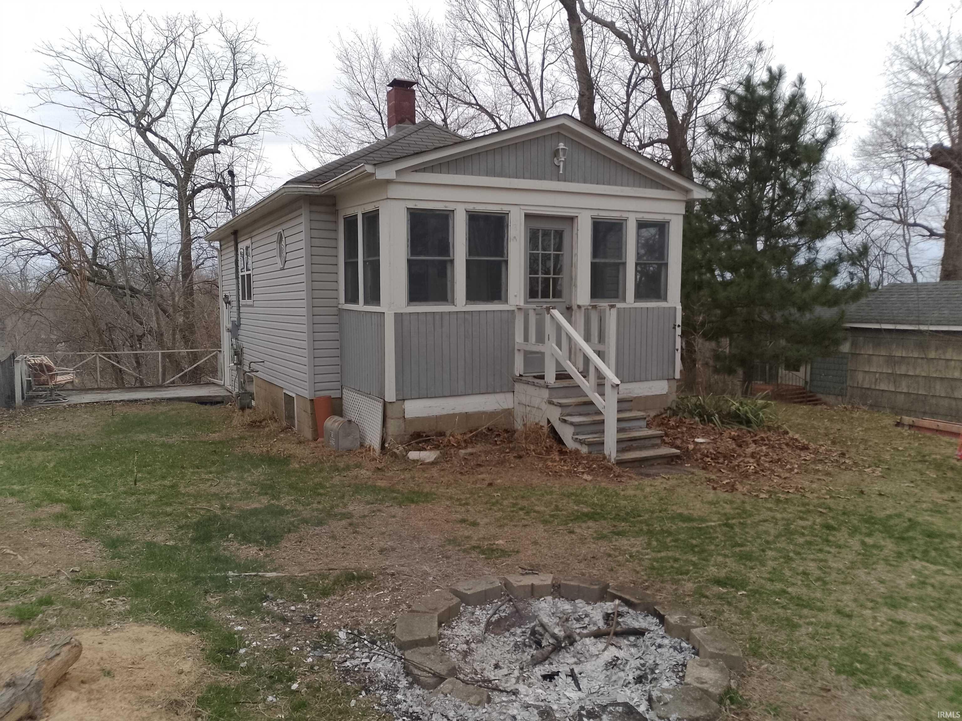 Image 0: View of front of home with a fire pit, a sunroom, and a chimney, Front Of Structure
