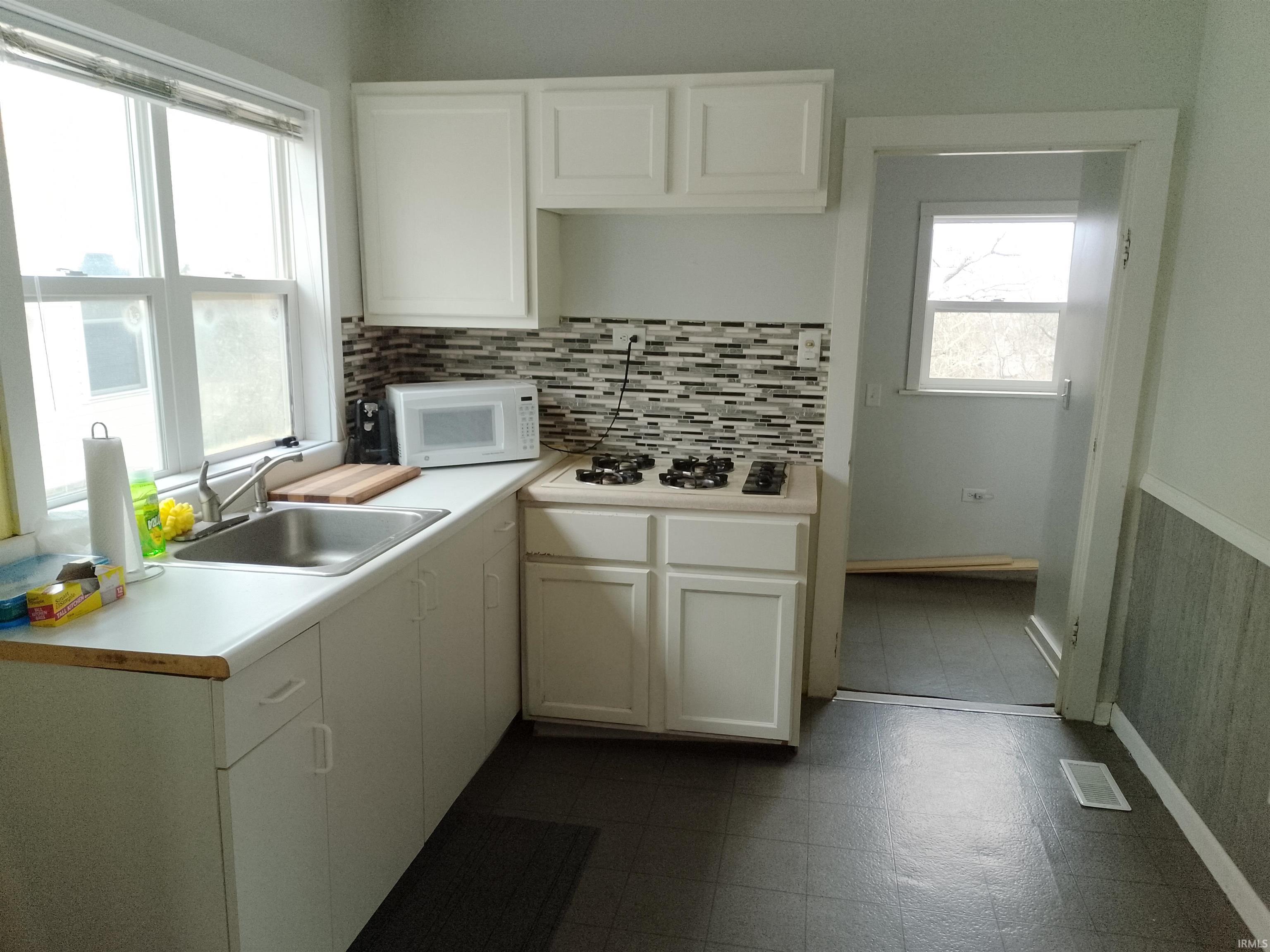 Image 2: Kitchen featuring light countertops, white cabinetry, white appliances, and dark floors, Kitchen