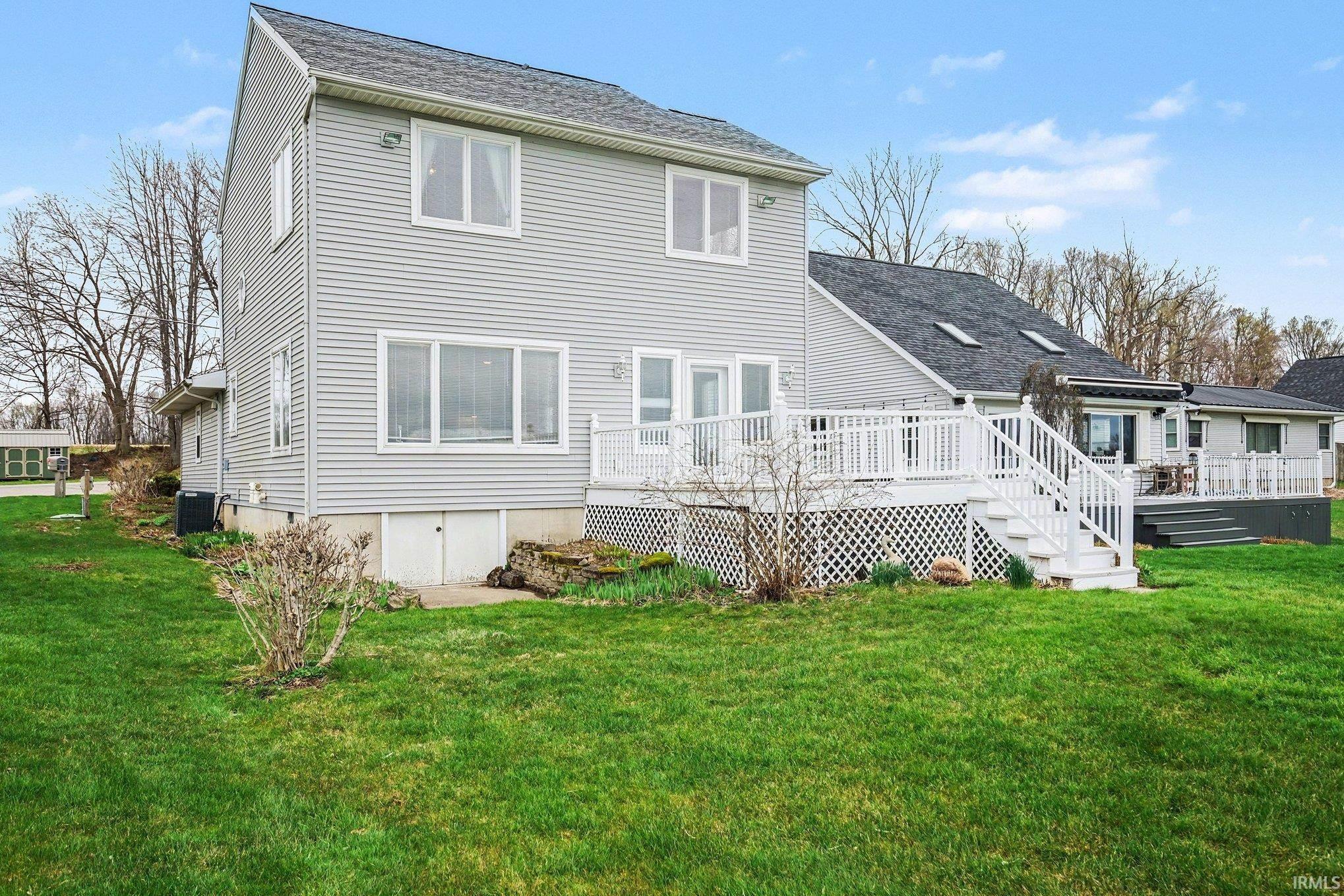 Image 1: Rear view of property featuring a lawn, a shingled roof, and a deck, Back Of Structure