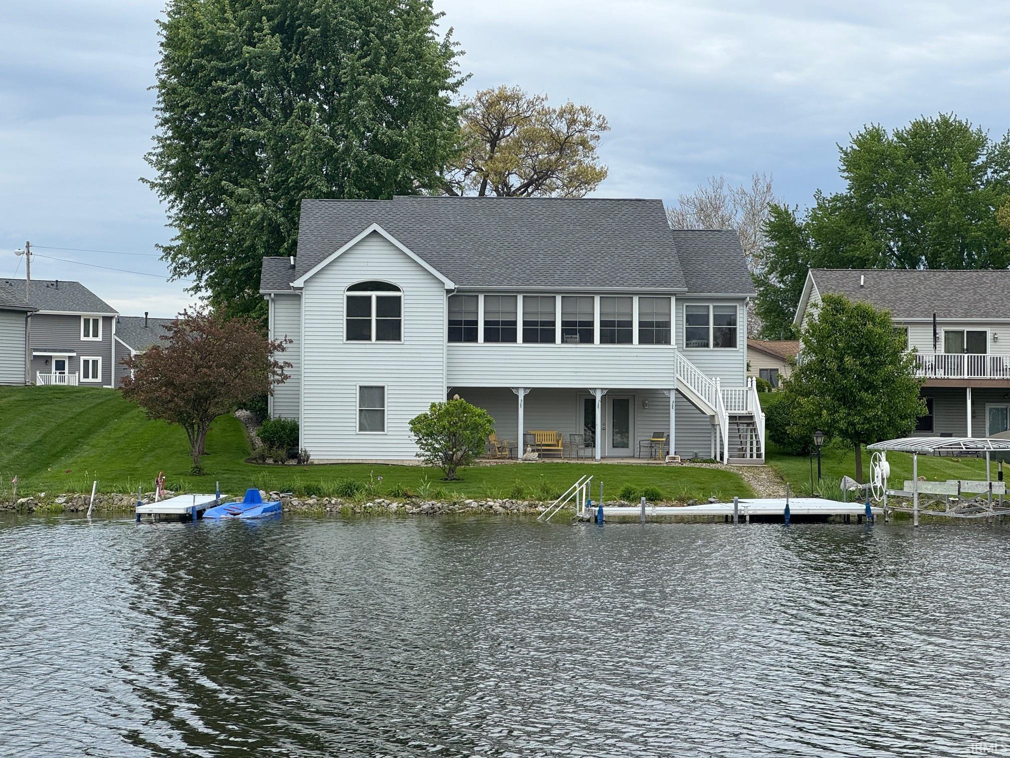 Image 0: Waterfront residence featuring light gray siding and a dark gray shingle roof, Back Of Structure