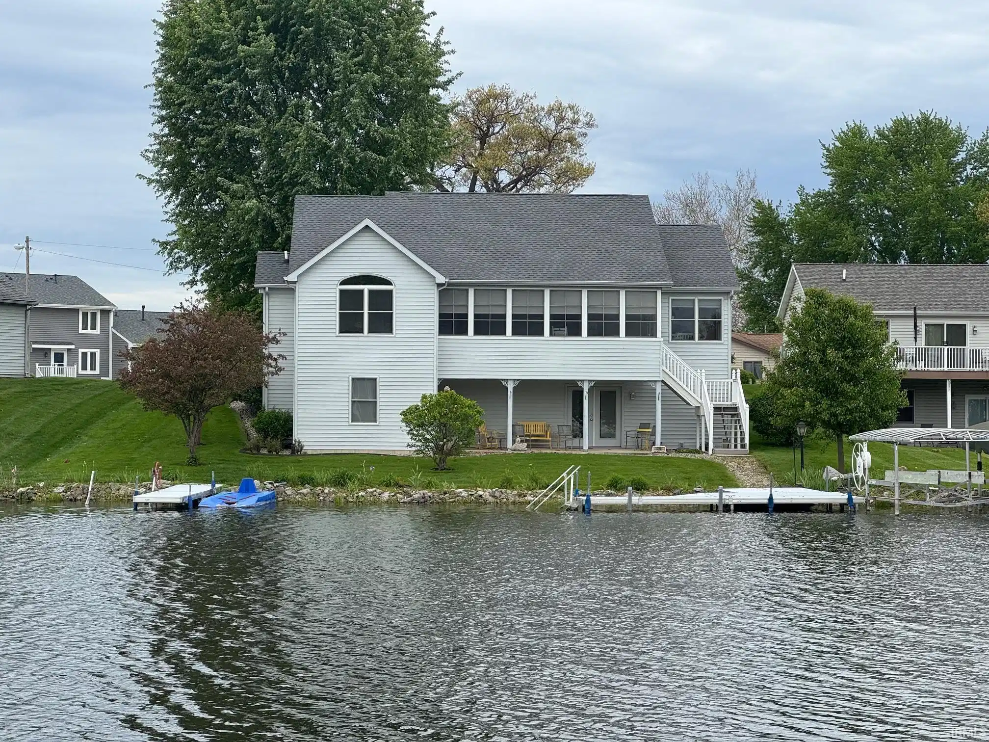 Image 0: Waterfront residence featuring light gray siding and a dark gray shingle roof, Back Of Structure Image 0: Waterfront residence featuring light gray siding and a dark gray shingle roof, Back Of Structure