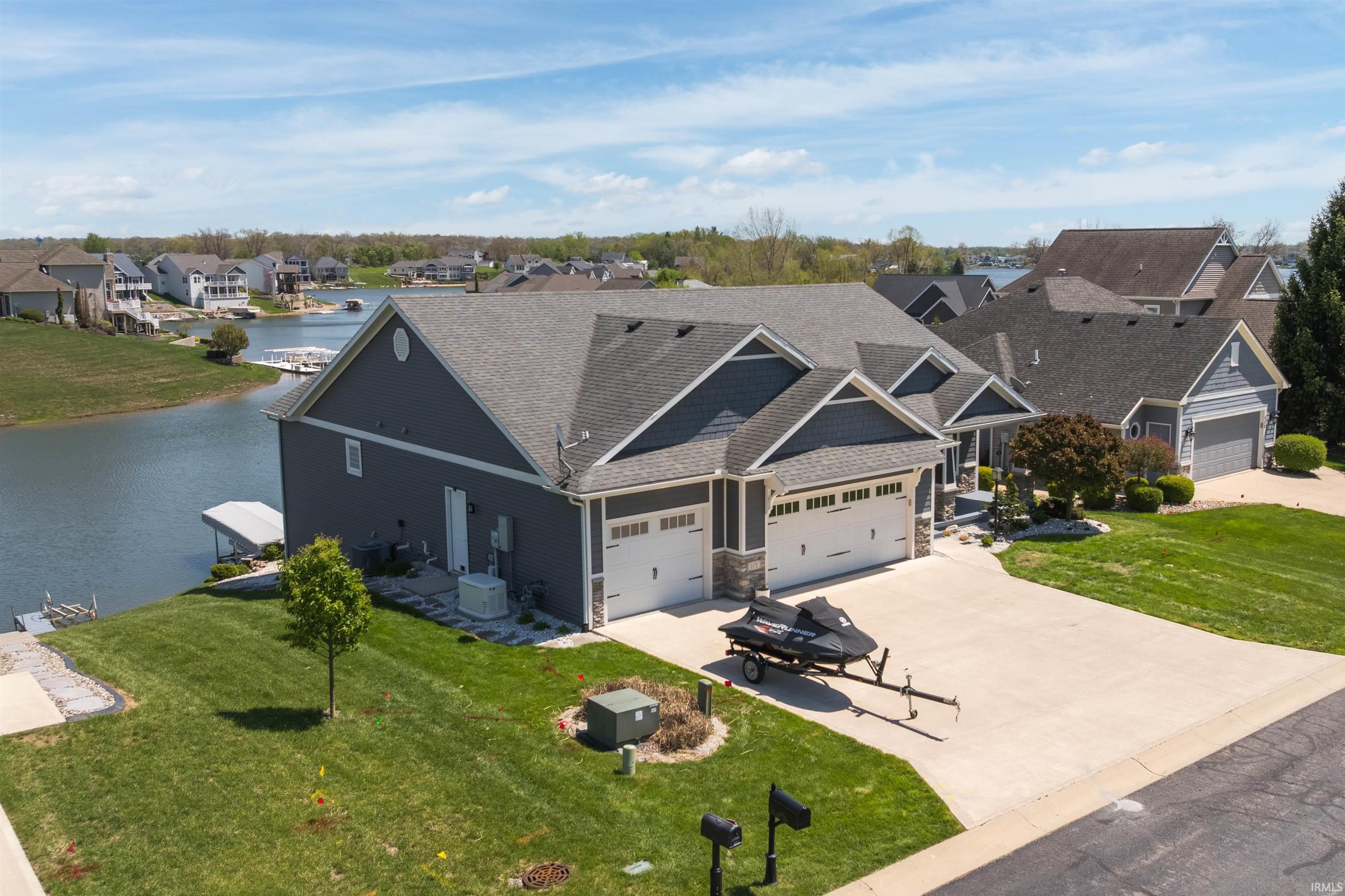 Image 1: Waterfront residence featuring a multi-car garage, gray siding with white trim, and a concrete driveway, Front Of Structure Image 1: Waterfront residence featuring a multi-car garage, gray siding with white trim, and a concrete driveway, Front Of Structure