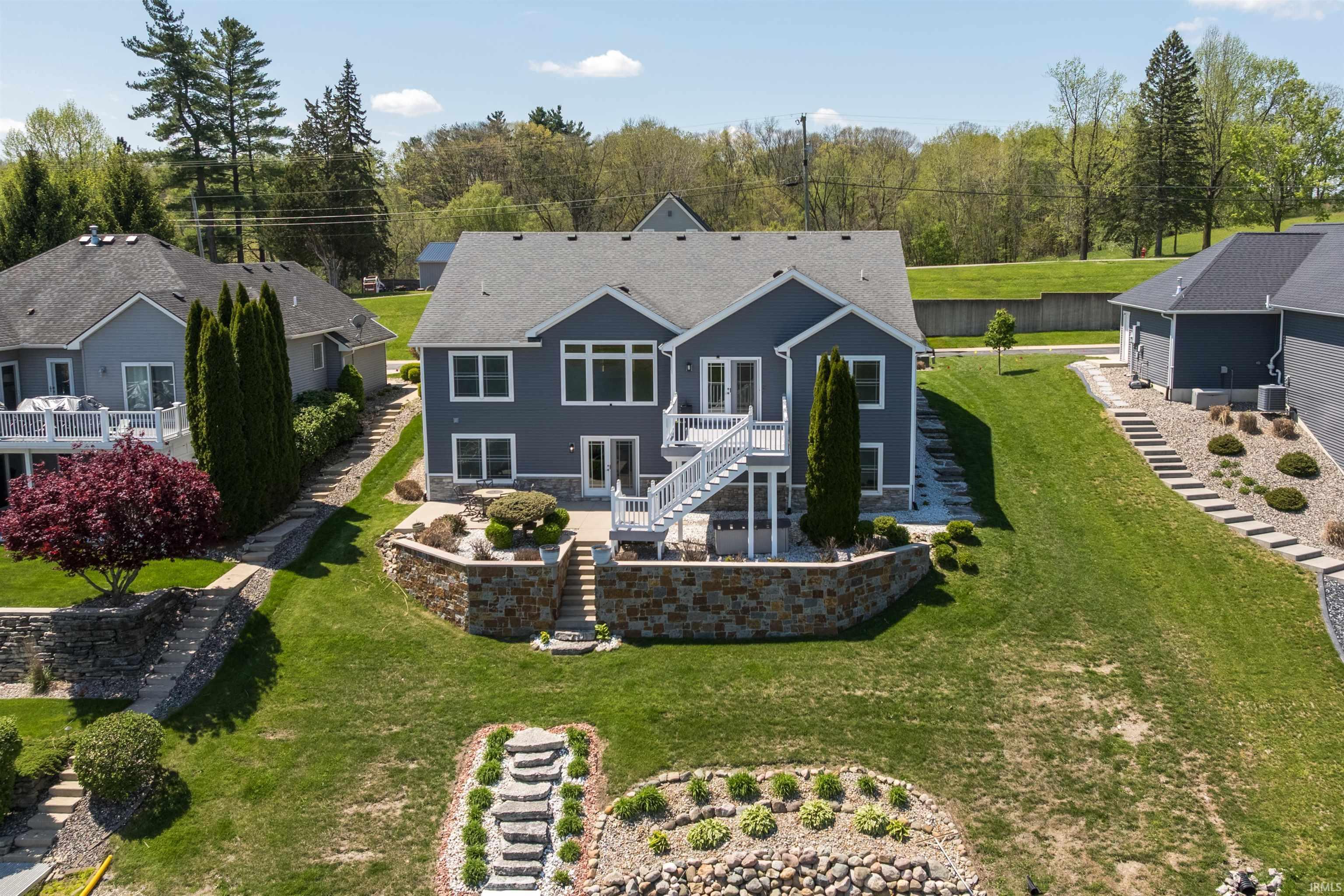 Image 2: Expansive rear exterior featuring a multi-level deck with white railings, a stone retaining wall, and a terraced lawn, Back Of Structure Image 2: Expansive rear exterior featuring a multi-level deck with white railings, a stone retaining wall, and a terraced lawn, Back Of Structure