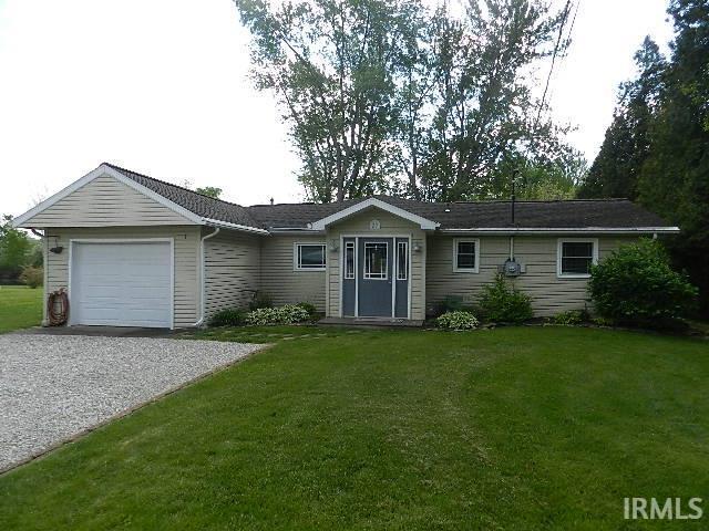 Image 2: Ranch-style residence featuring light-colored siding, an attached garage, a gravel driveway, a grassy lawn, and mature trees, Front Of Structure Image 2: Ranch-style residence featuring light-colored siding, an attached garage, a gravel driveway, a grassy lawn, and mature trees, Front Of Structure