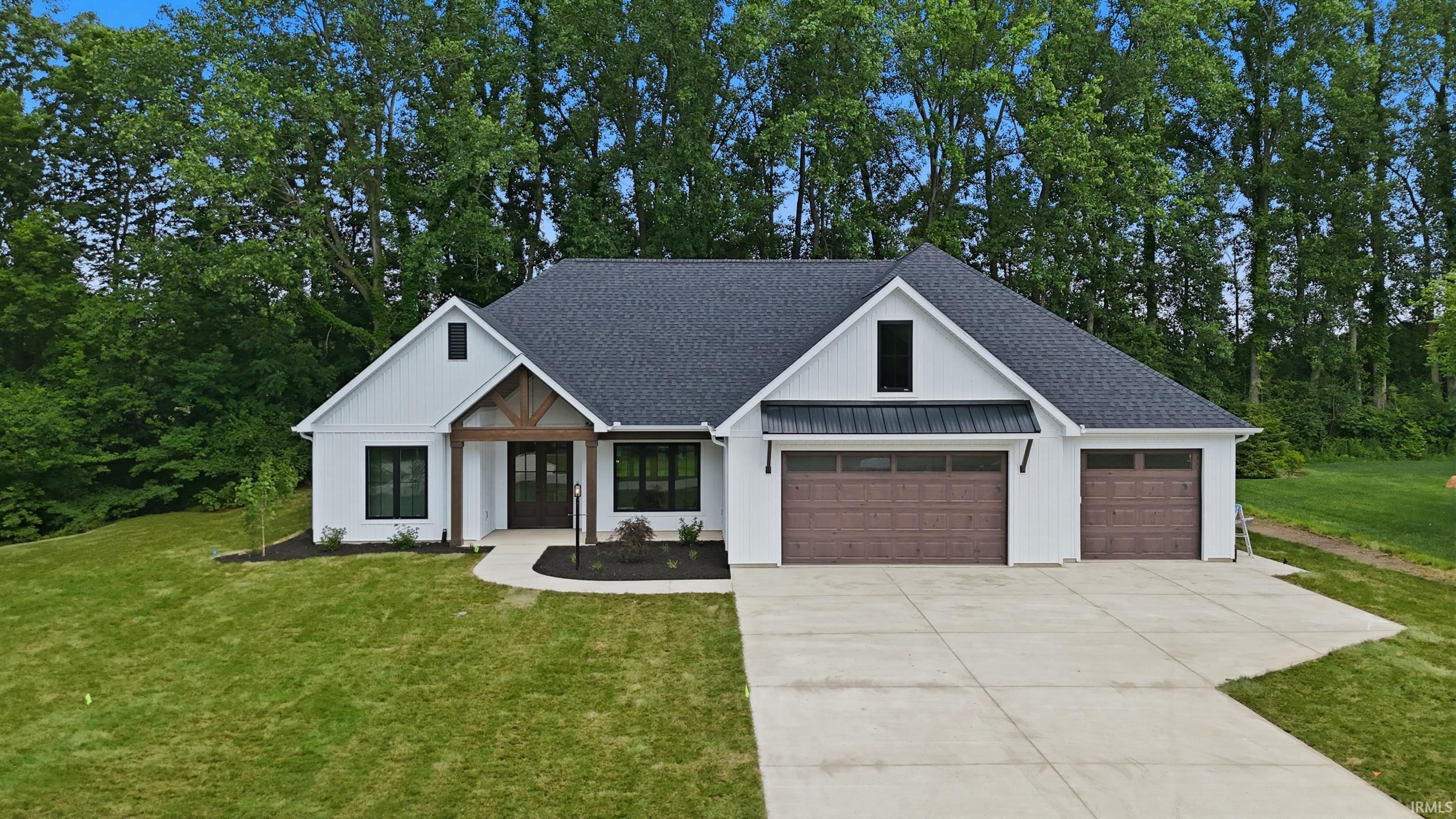 Image 0: Modern farmhouse exterior with white board and batten siding, dark shingle roof, and a prominent gable featuring exposed wood beams, Front Of Structure