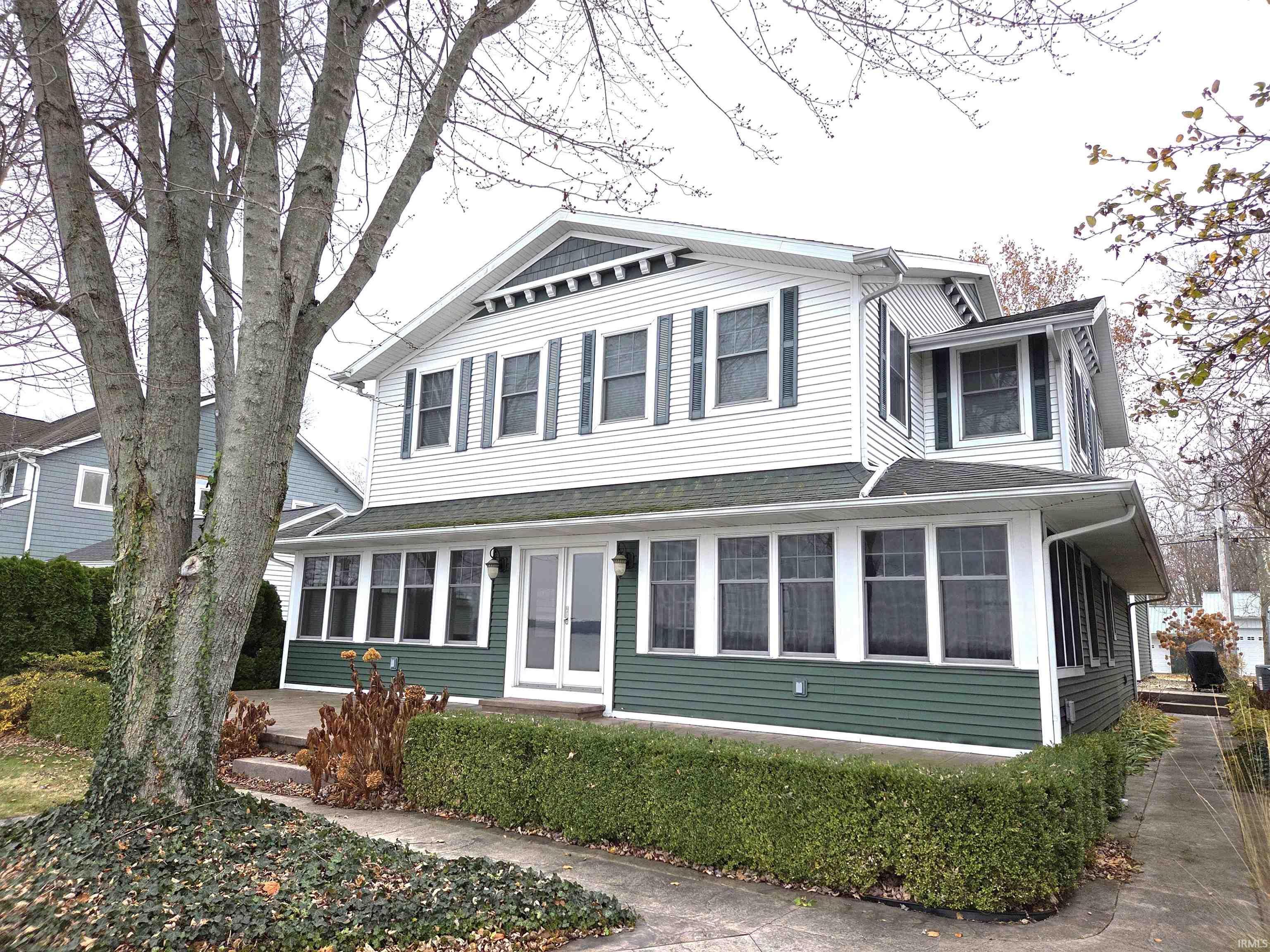 Image 0: View of front of property featuring a sunroom and a shingled roof, Front Of Structure