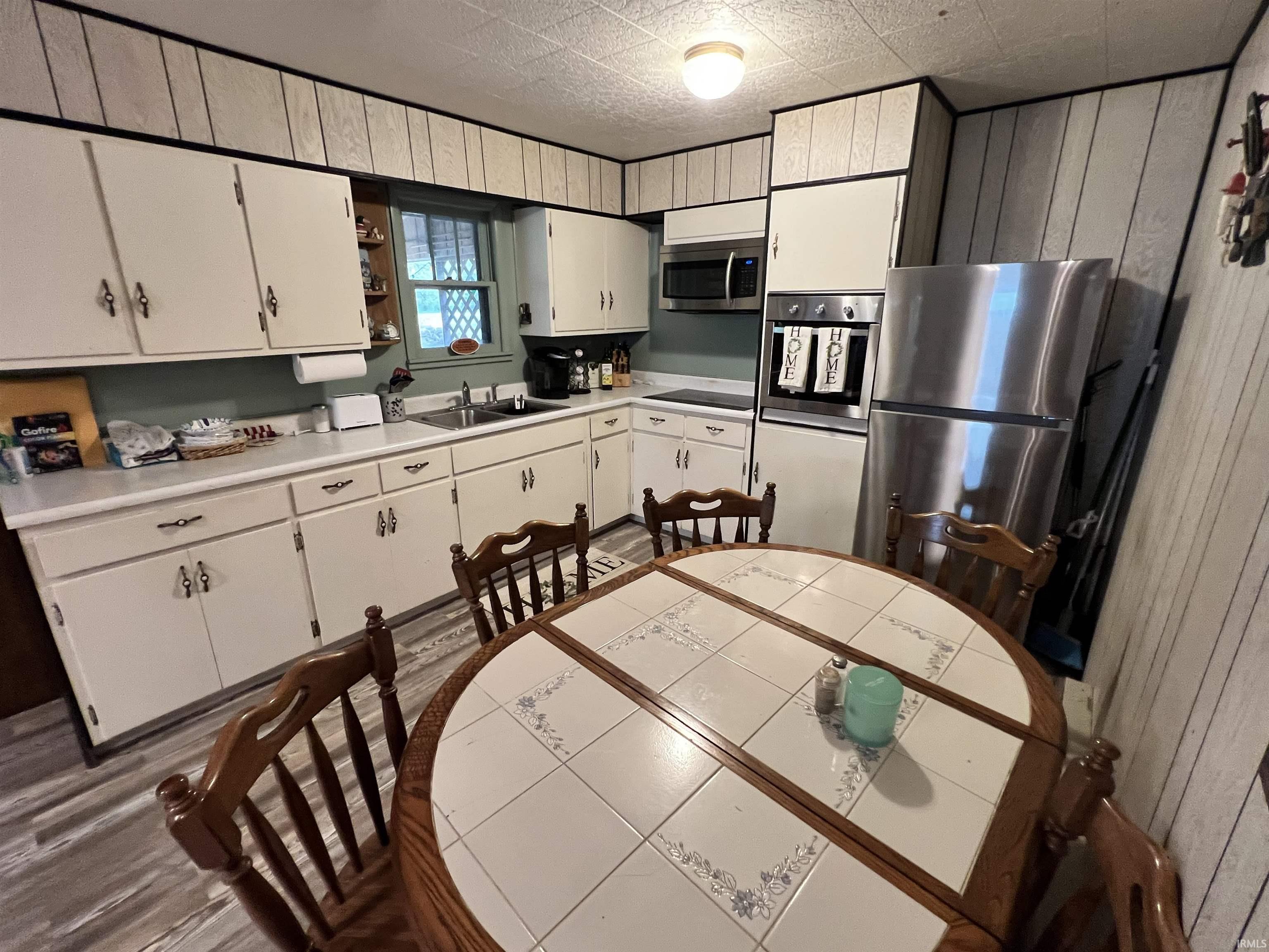 Image 3: Kitchen featuring white cabinetry, light countertops, wood-finish flooring, stainless steel appliances, and a built-in wall oven, Kitchen Image 3: Kitchen featuring white cabinetry, light countertops, wood-finish flooring, stainless steel appliances, and a built-in wall oven, Kitchen