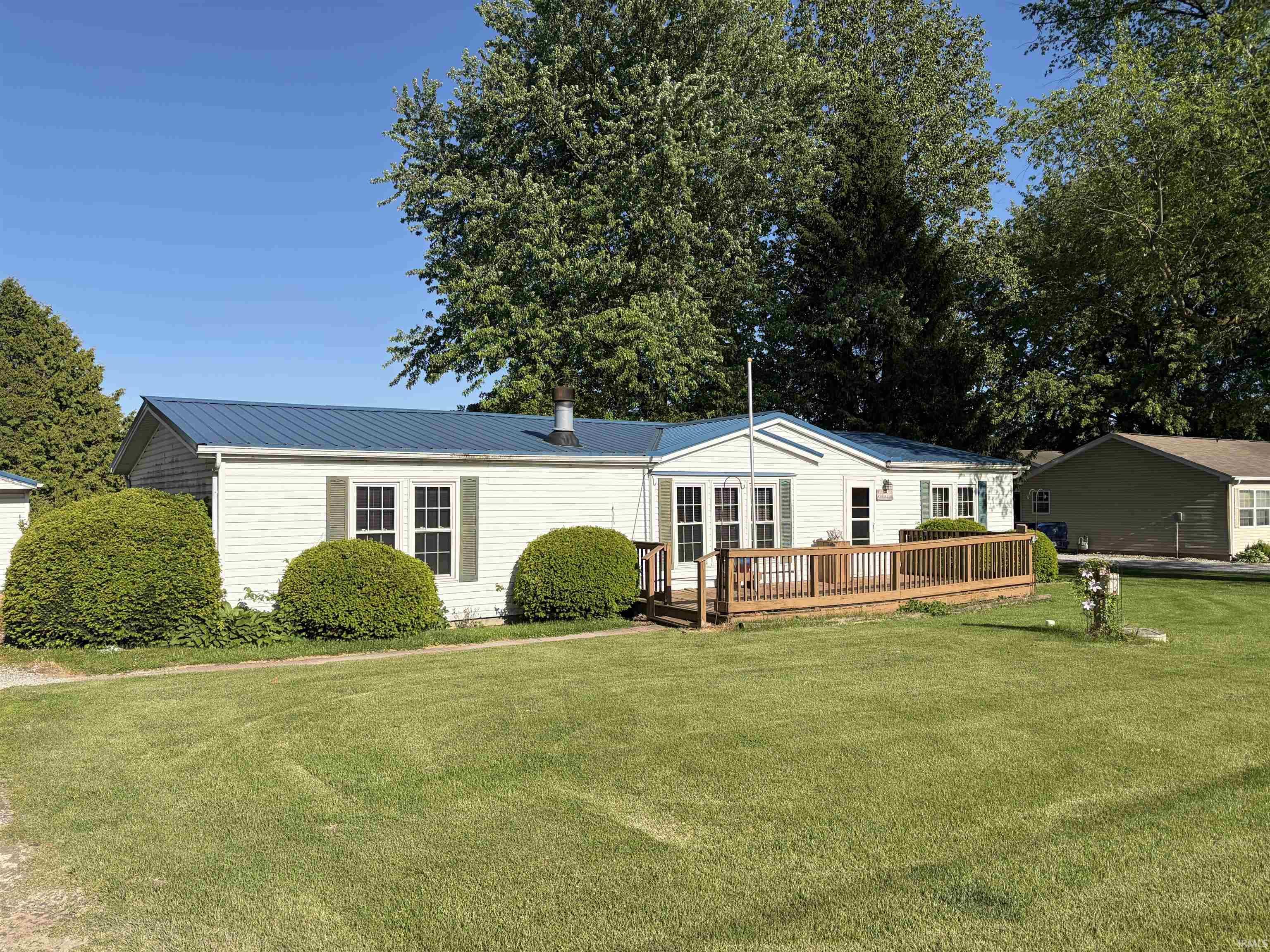 Image 1: Single-story residence featuring white siding and a blue metal roof, Front Of Structure