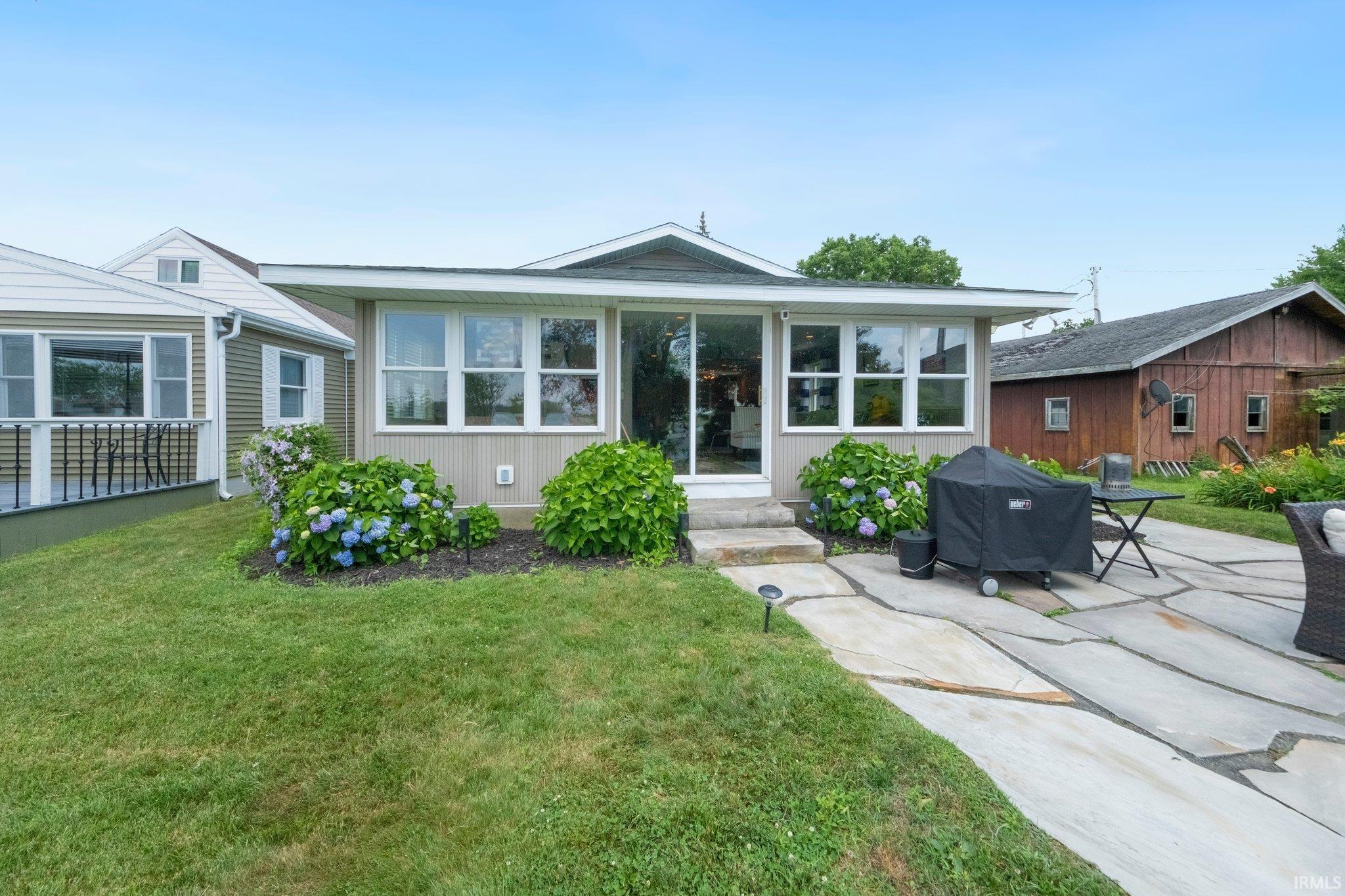 Image 1: Rear exterior featuring a flagstone patio, manicured lawn, and mature landscaping, Back Of Structure Image 1: Rear exterior featuring a flagstone patio, manicured lawn, and mature landscaping, Back Of Structure
