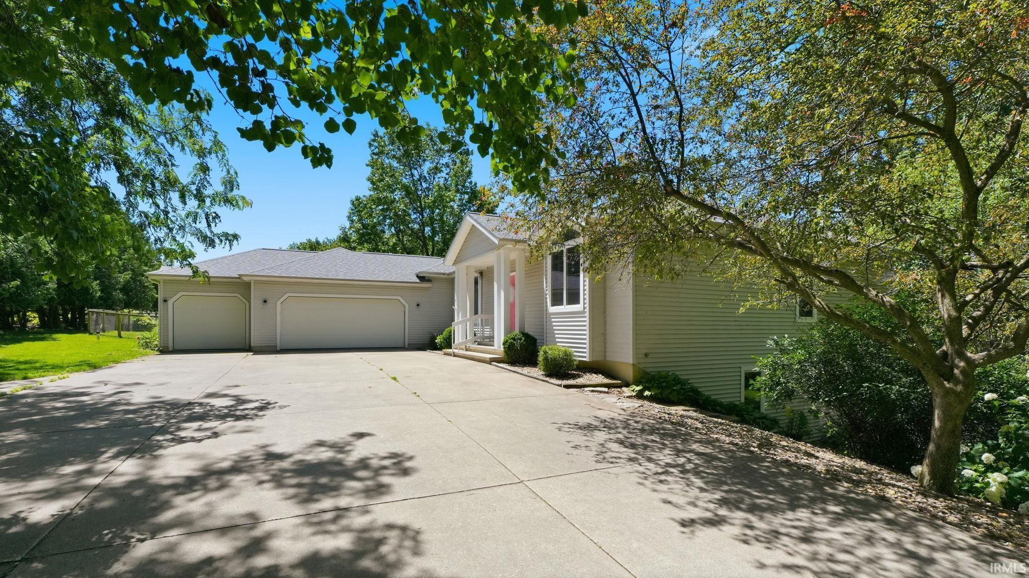 Image 1: Ranch-style exterior with light-colored siding, featuring a multi-car garage, a concrete driveway, and mature landscaping, Front Of Structure Image 1: Ranch-style exterior with light-colored siding, featuring a multi-car garage, a concrete driveway, and mature landscaping, Front Of Structure