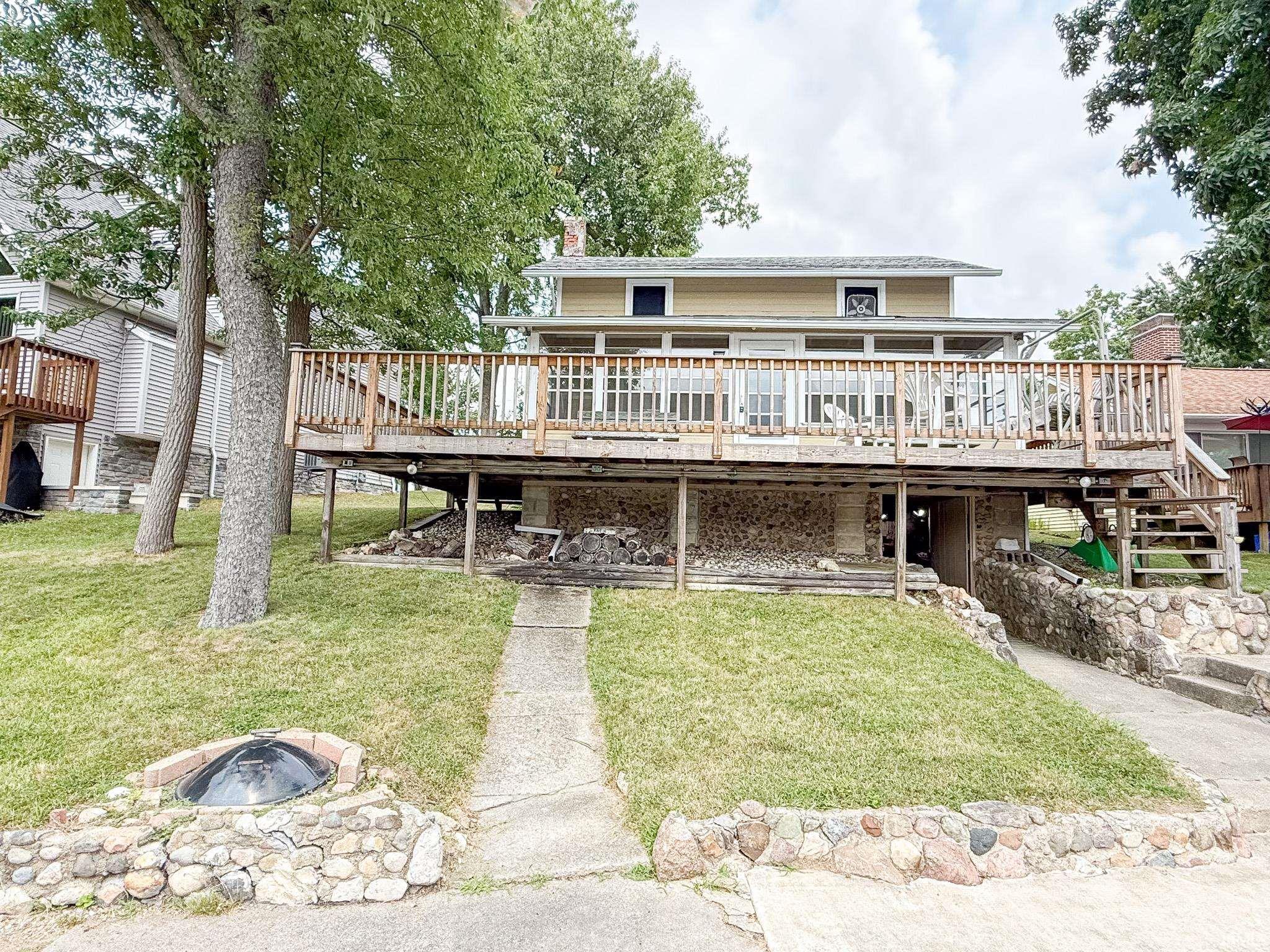 Image 0: Two-story home with a large wood deck featuring a natural wood railing, Lakefront Image 0: Two-story home with a large wood deck featuring a natural wood railing, Lakefront