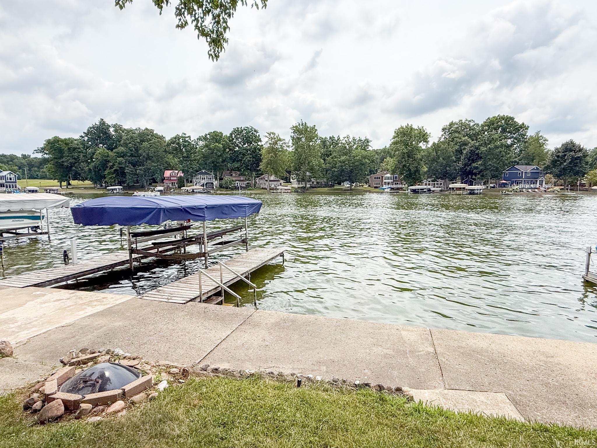 Image 1: Waterfront property featuring multiple boat docks with a stone and brick fire pit, and a concrete patio, Dock Image 1: Waterfront property featuring multiple boat docks with a stone and brick fire pit, and a concrete patio, Dock