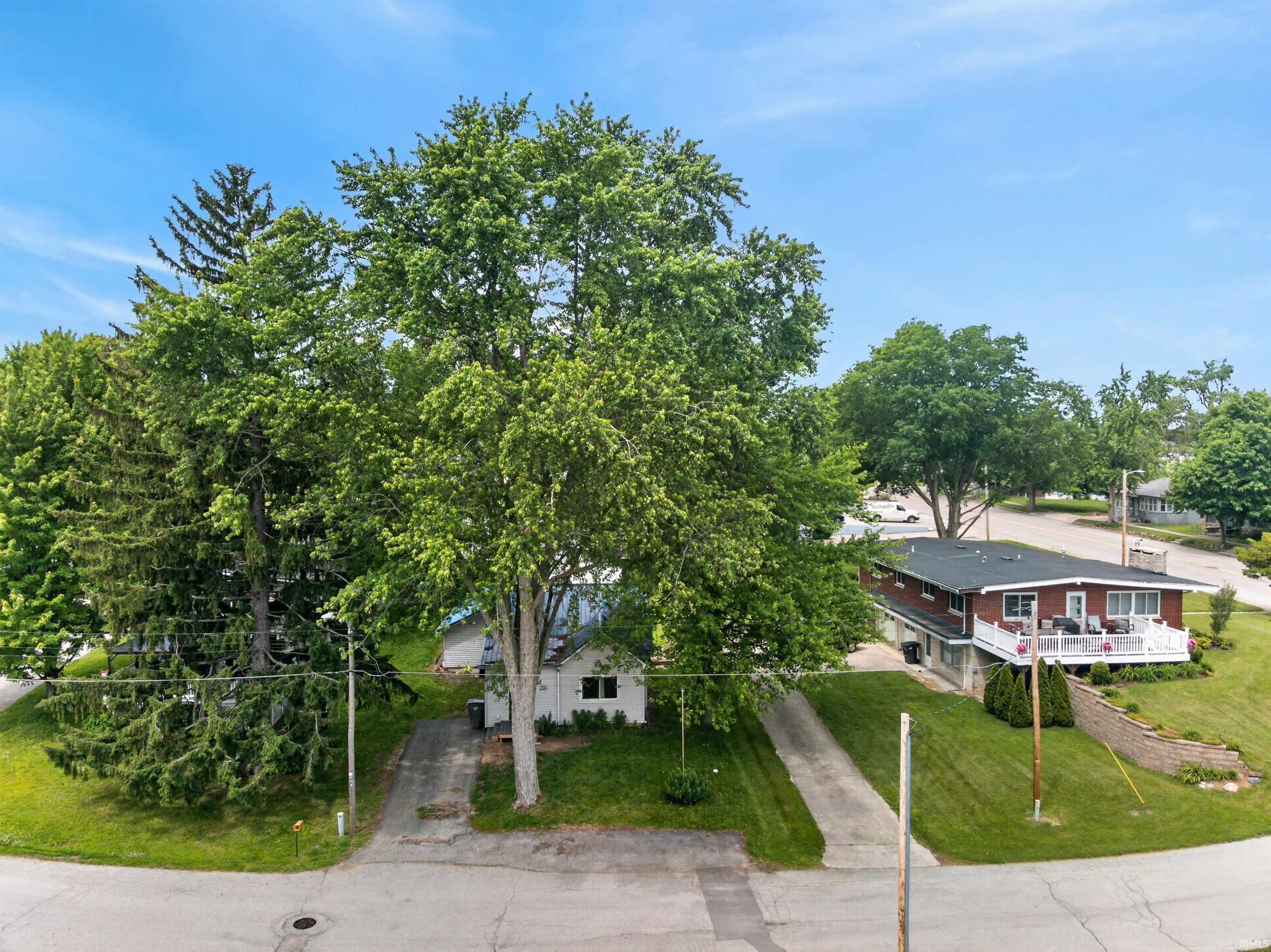 Image 2: Elevated residence featuring a red brick exterior, white railing deck, and a dark shingle roof, Aerial View Image 2: Elevated residence featuring a red brick exterior, white railing deck, and a dark shingle roof, Aerial View