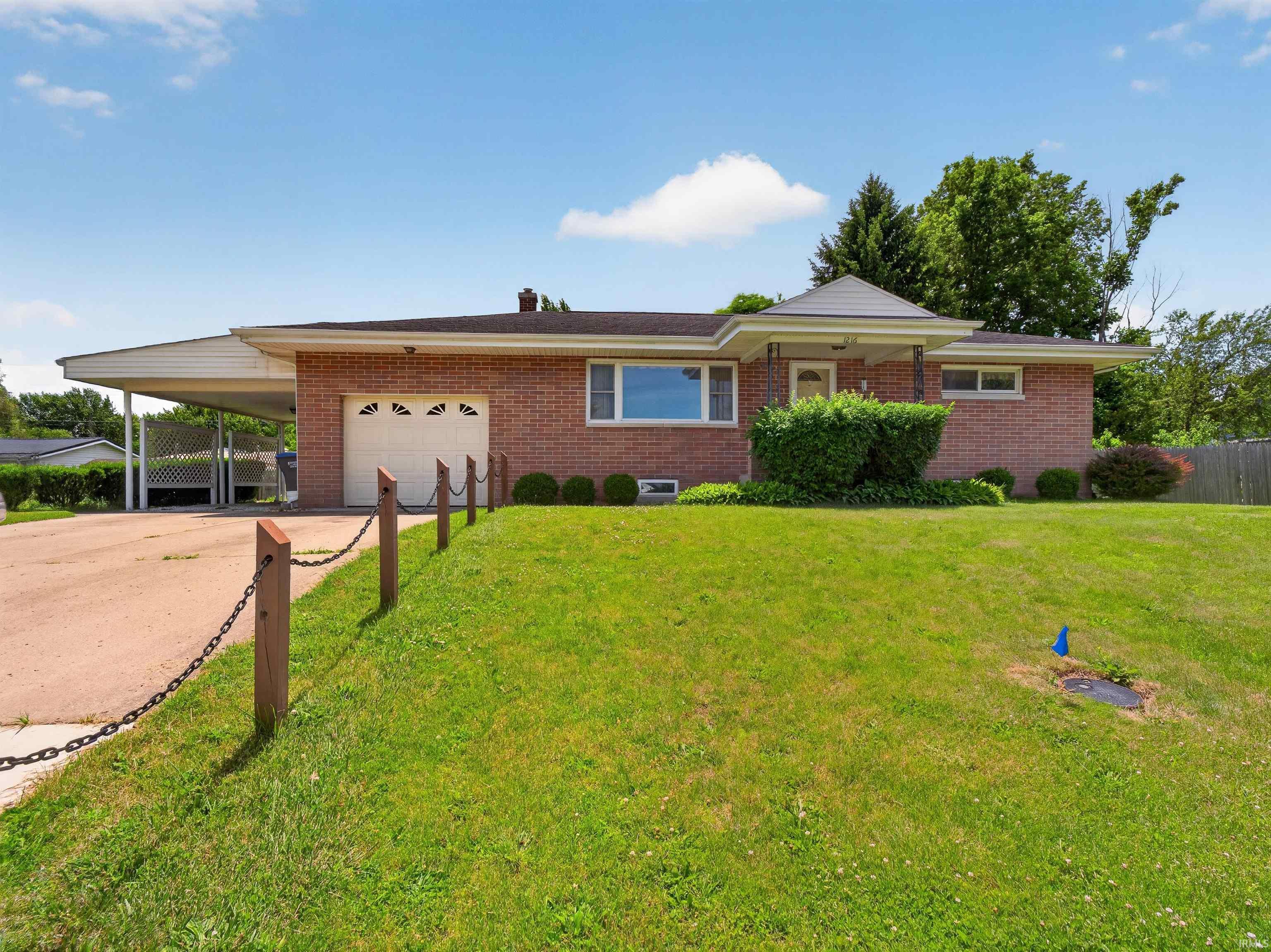 Image 0: Brick ranch-style home featuring a covered carport, attached garage, and a covered entryway, Front Of Structure