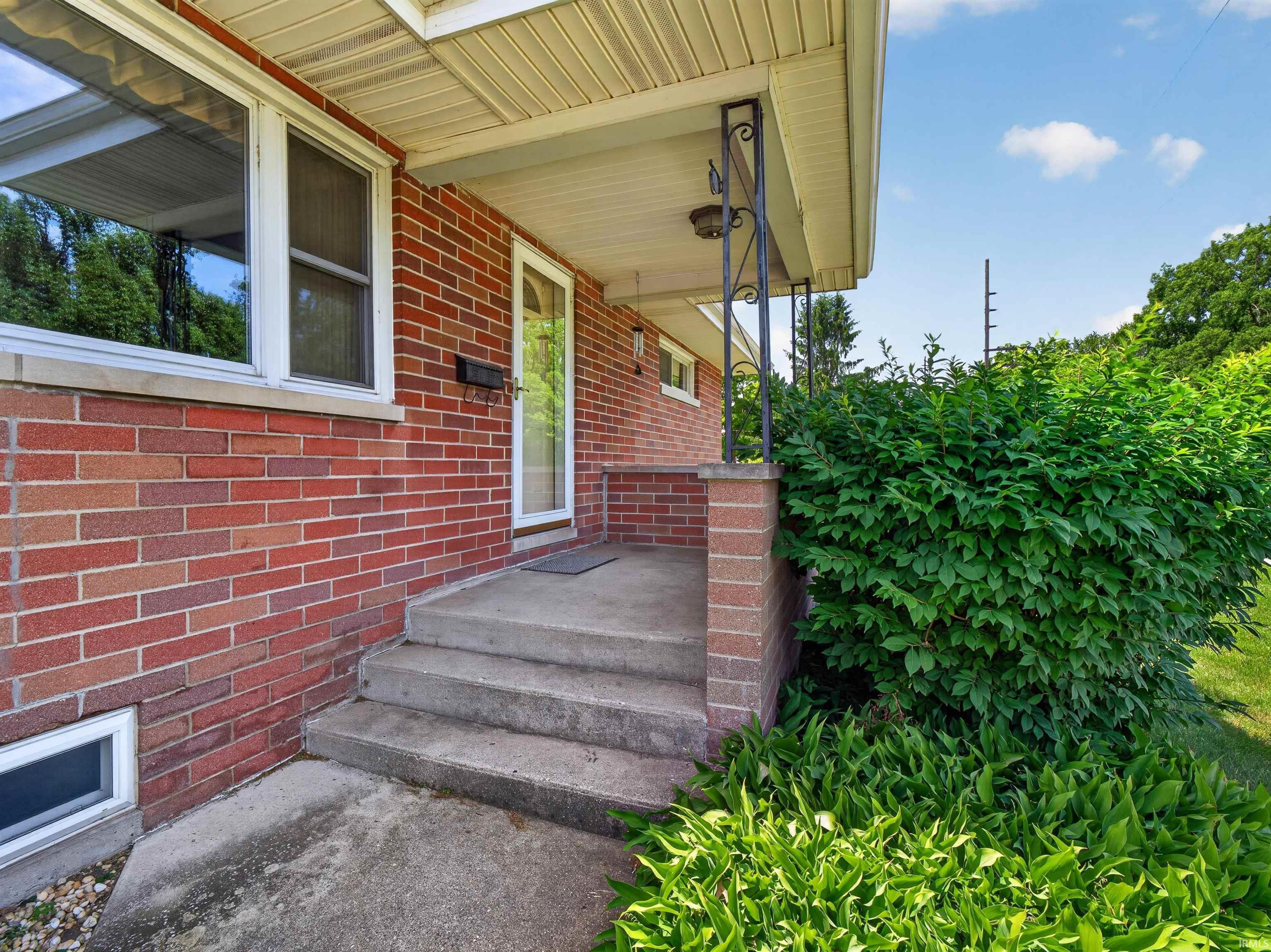 Image 3: Brick facade with a covered porch featuring decorative metal columns, Entry