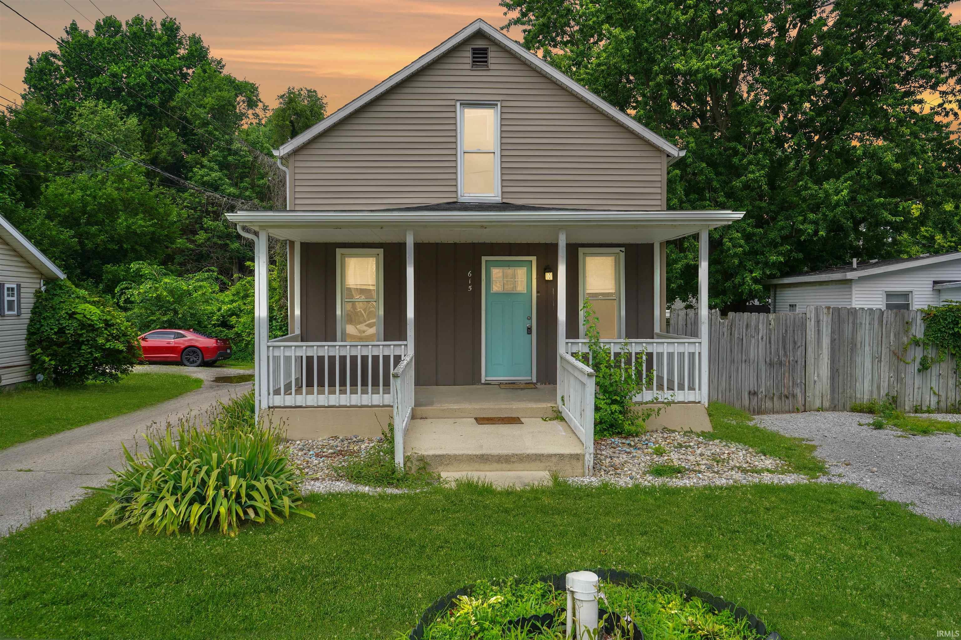 Image 1: Two-story residence featuring a covered front porch with white railings, a vibrant blue entry door, and light brown siding, Front Of Structure