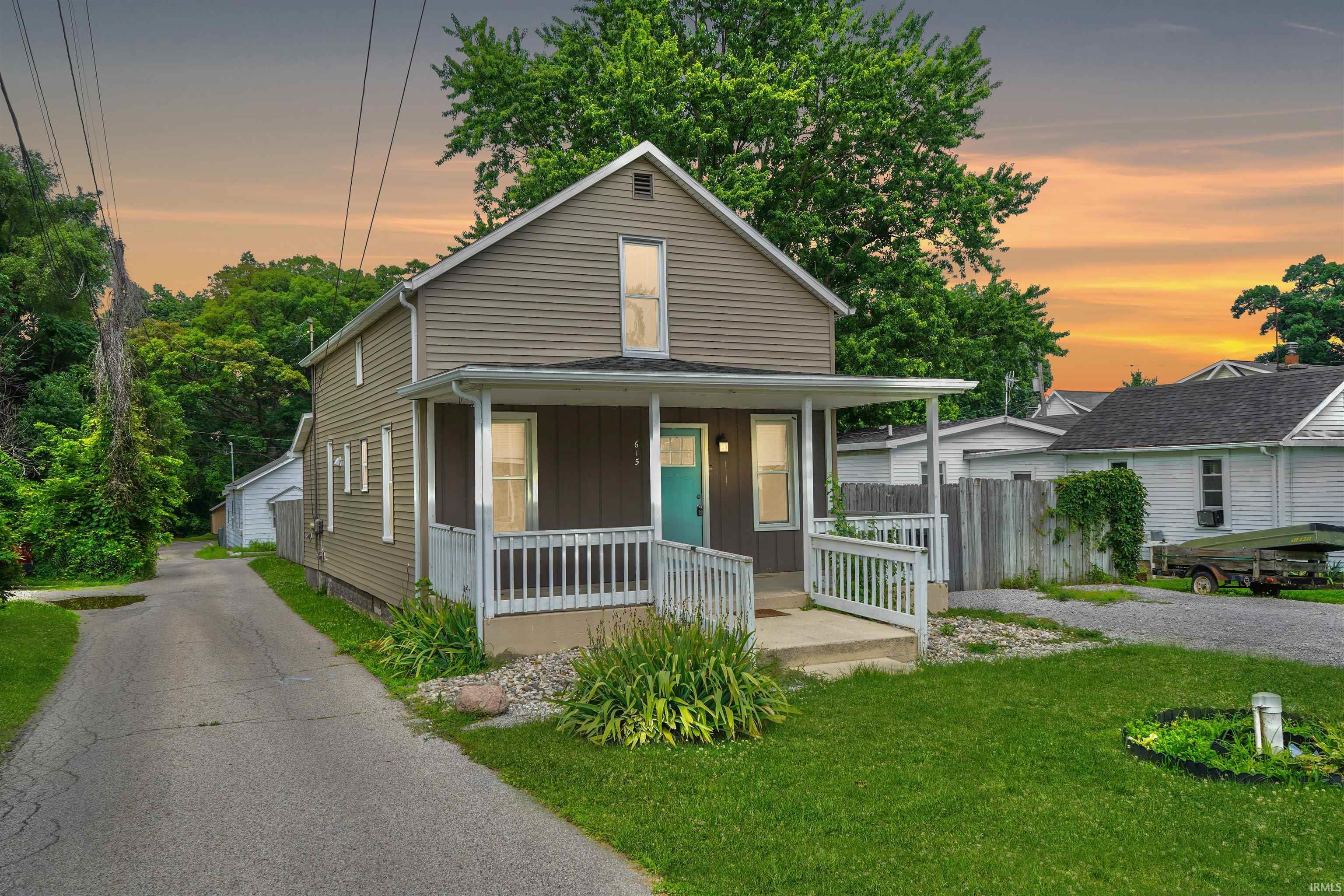 Image 2: Two-story residence featuring horizontal siding and a covered front porch with white railings, Front Of Structure
