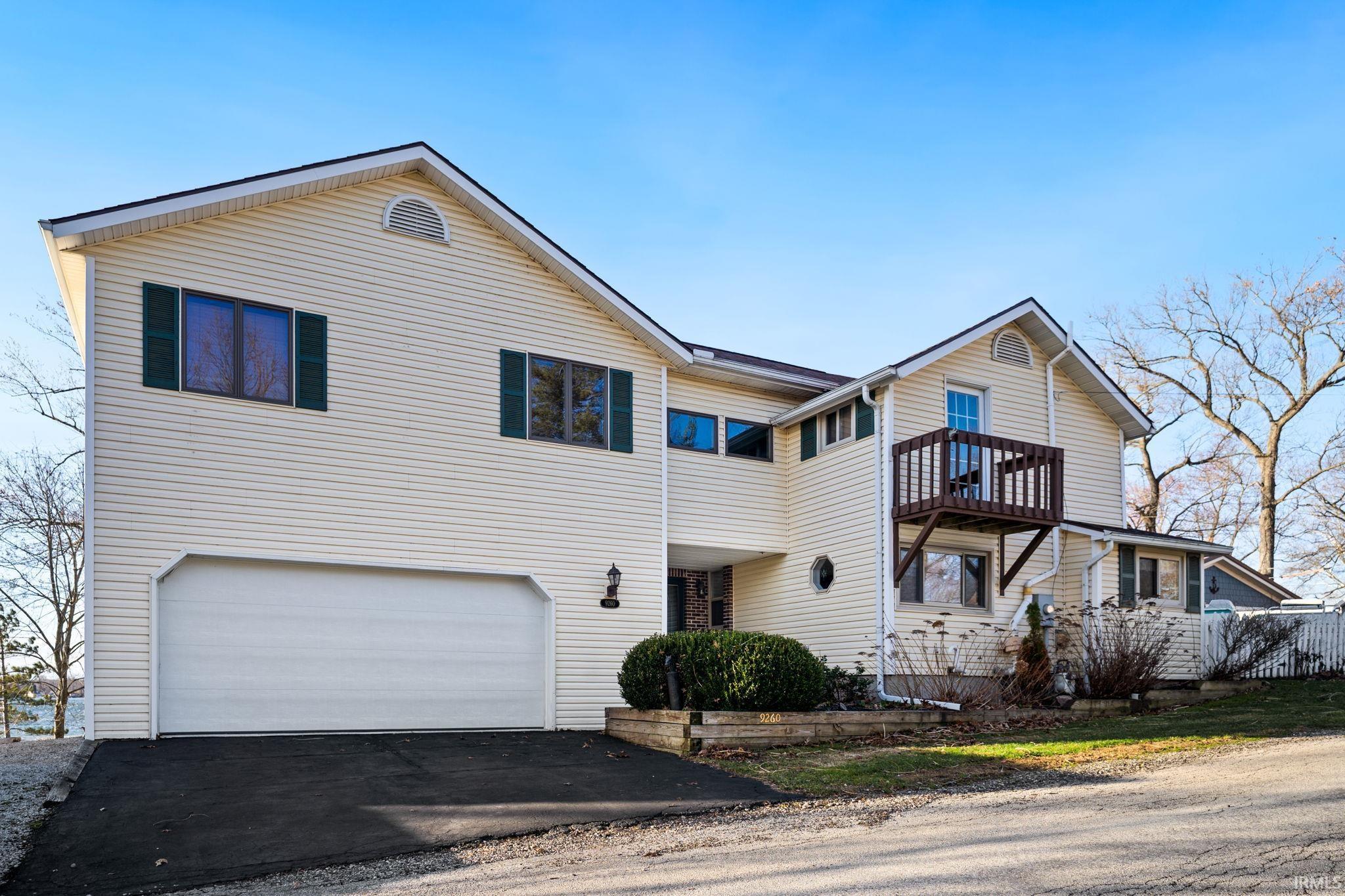 Image 0: Traditional-style home featuring an attached garage, driveway, and a balcony, Front Of Structure