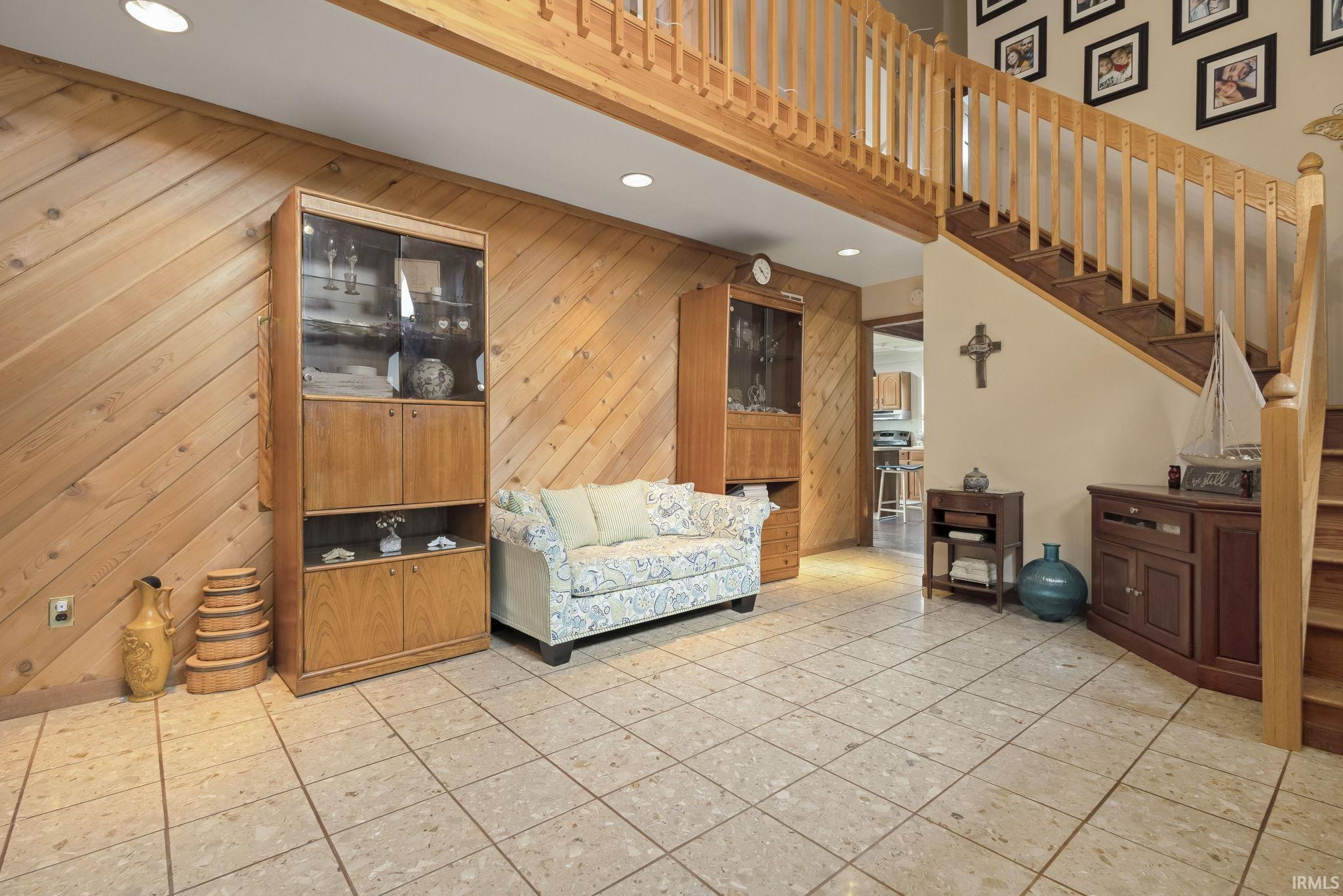 Image 2: Living room featuring recessed lighting, light tile patterned floors, wooden walls, and a high ceiling, Living Room