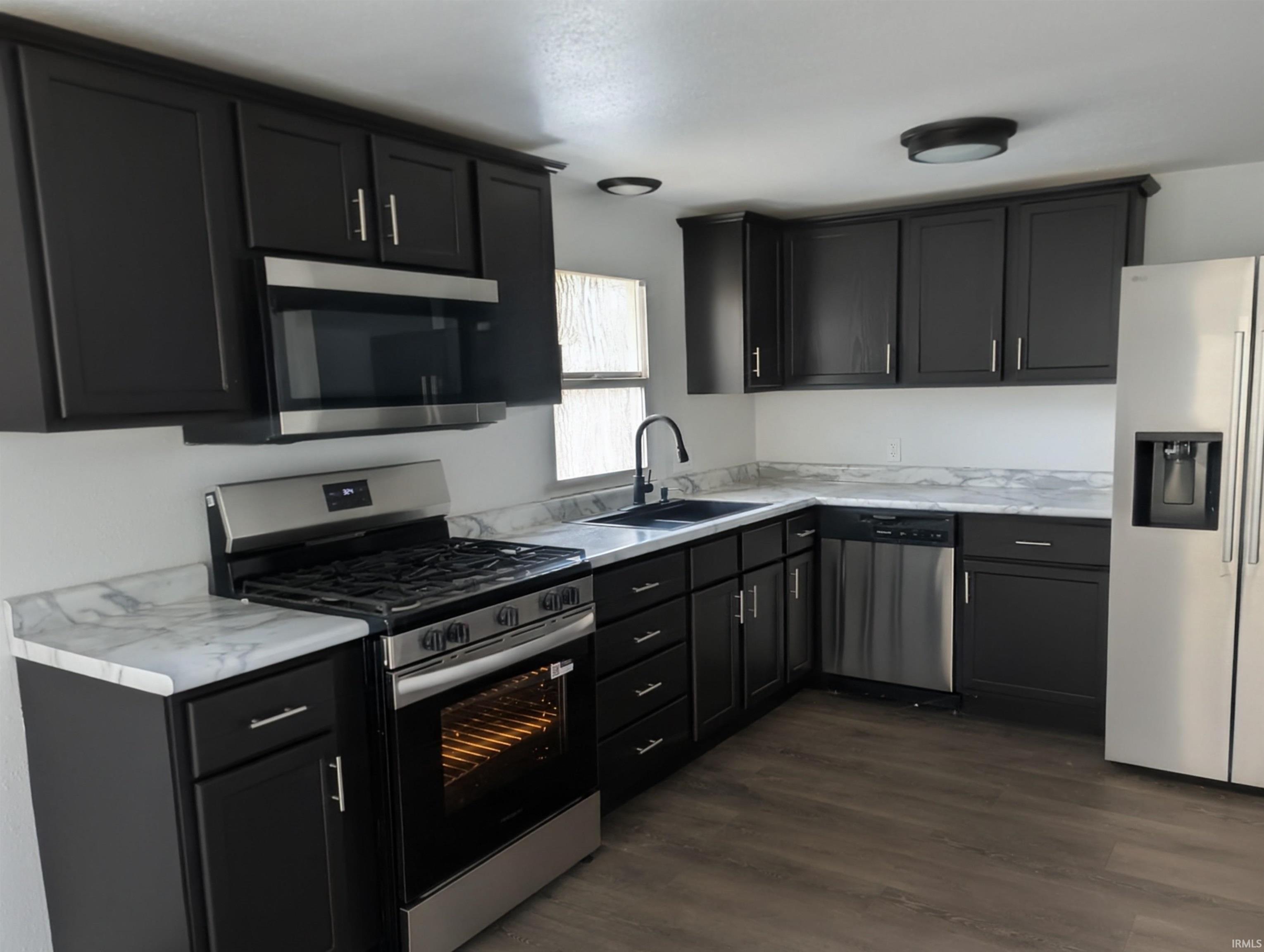 Image 2: Kitchen with stainless steel appliances, light countertops, dark cabinets, and dark wood-style floors, Kitchen Image 2: Kitchen with stainless steel appliances, light countertops, dark cabinets, and dark wood-style floors, Kitchen