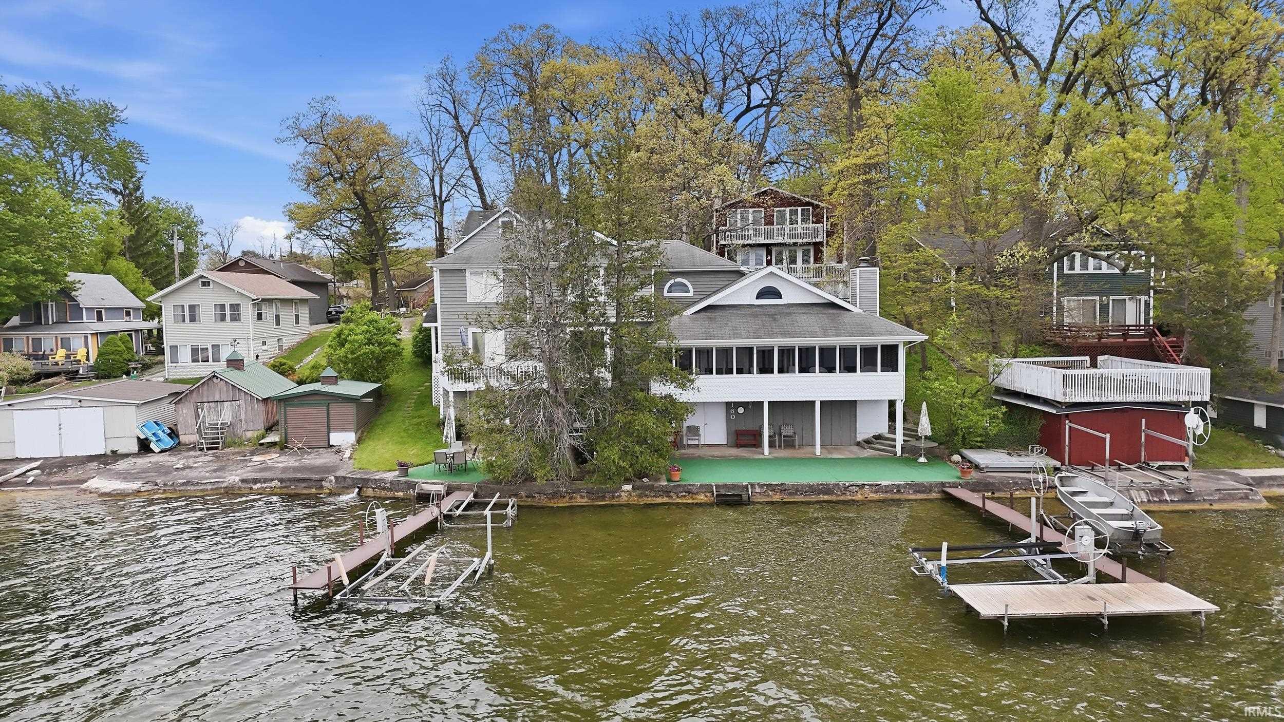 Image 1: Waterfront property featuring a multi-level structure with a covered porch and an arched window dormer, Dock