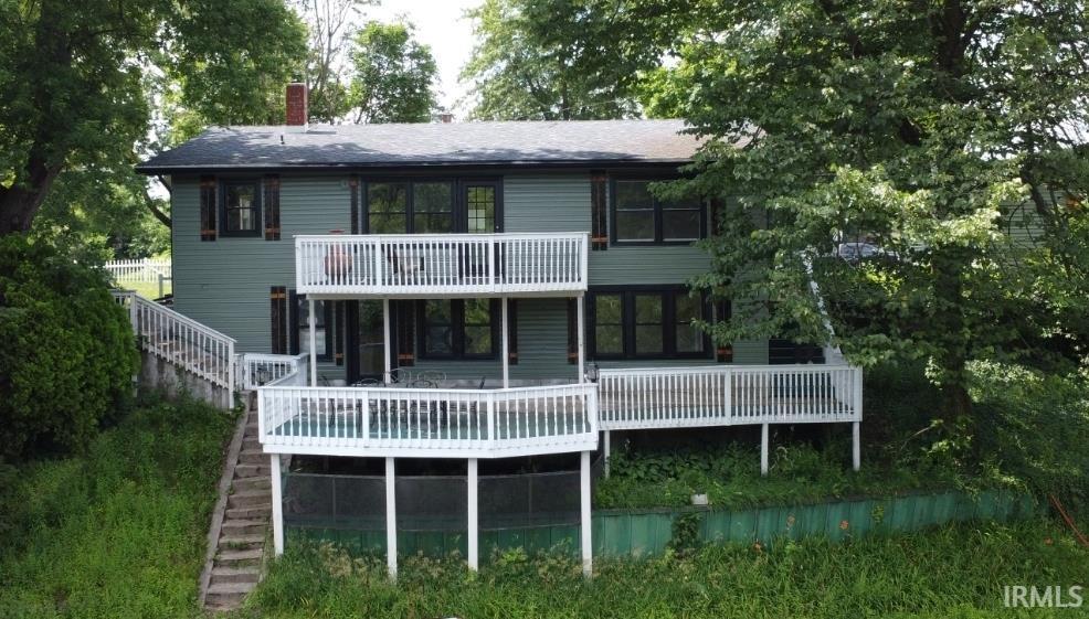 Image 1: Two-story siding exterior with a dark shingled roof and red brick chimney, Back Of Structure