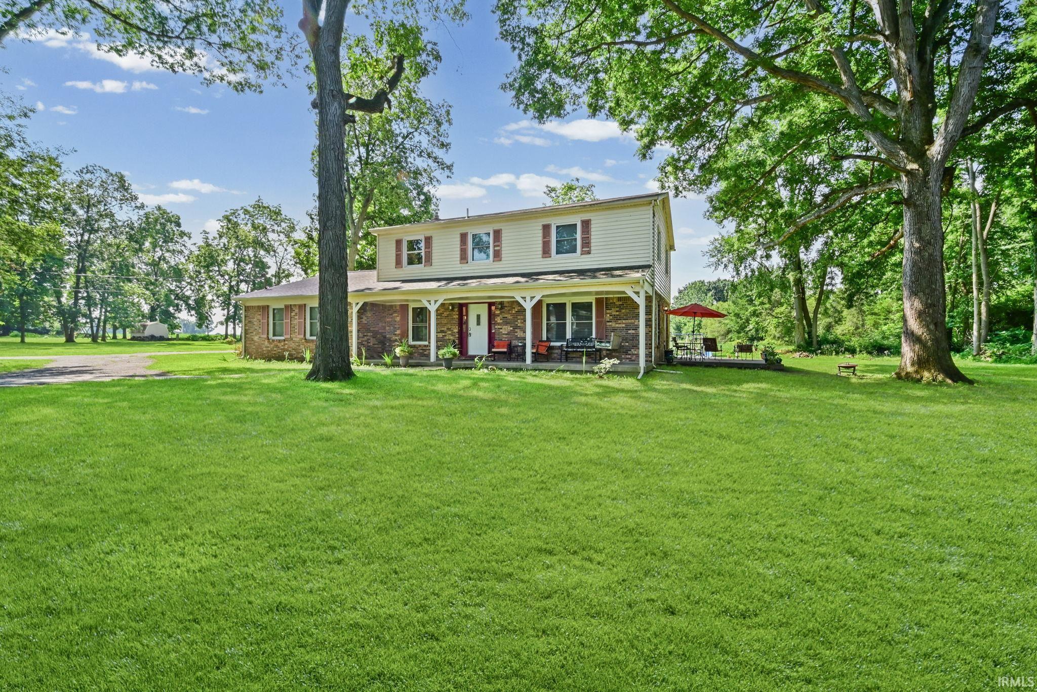 Image 3: Two-story residence featuring a covered front porch, brick and stone veneer accents, and cream siding with red shutters, Front Of Structure Image 3: Two-story residence featuring a covered front porch, brick and stone veneer accents, and cream siding with red shutters, Front Of Structure