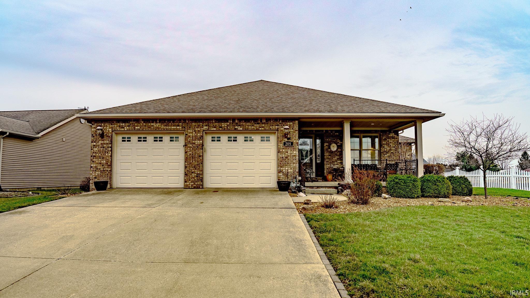 Image 1: View of front of house with covered porch, roof with shingles, brick siding, driveway, and a garage, Front Of Structure