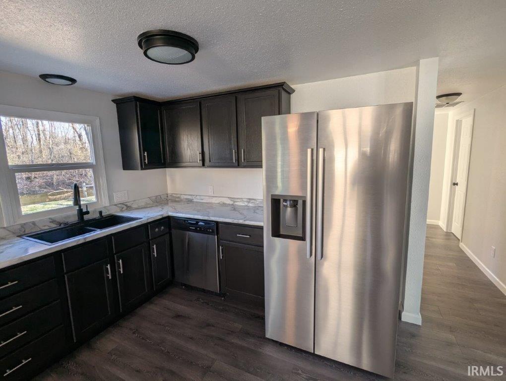 Image 3: Kitchen with stainless steel appliances, dark wood-type flooring, a textured ceiling, light stone counters, and dark wood finish cabinetry, Kitchen Image 3: Kitchen with stainless steel appliances, dark wood-type flooring, a textured ceiling, light stone counters, and dark wood finish cabinetry, Kitchen