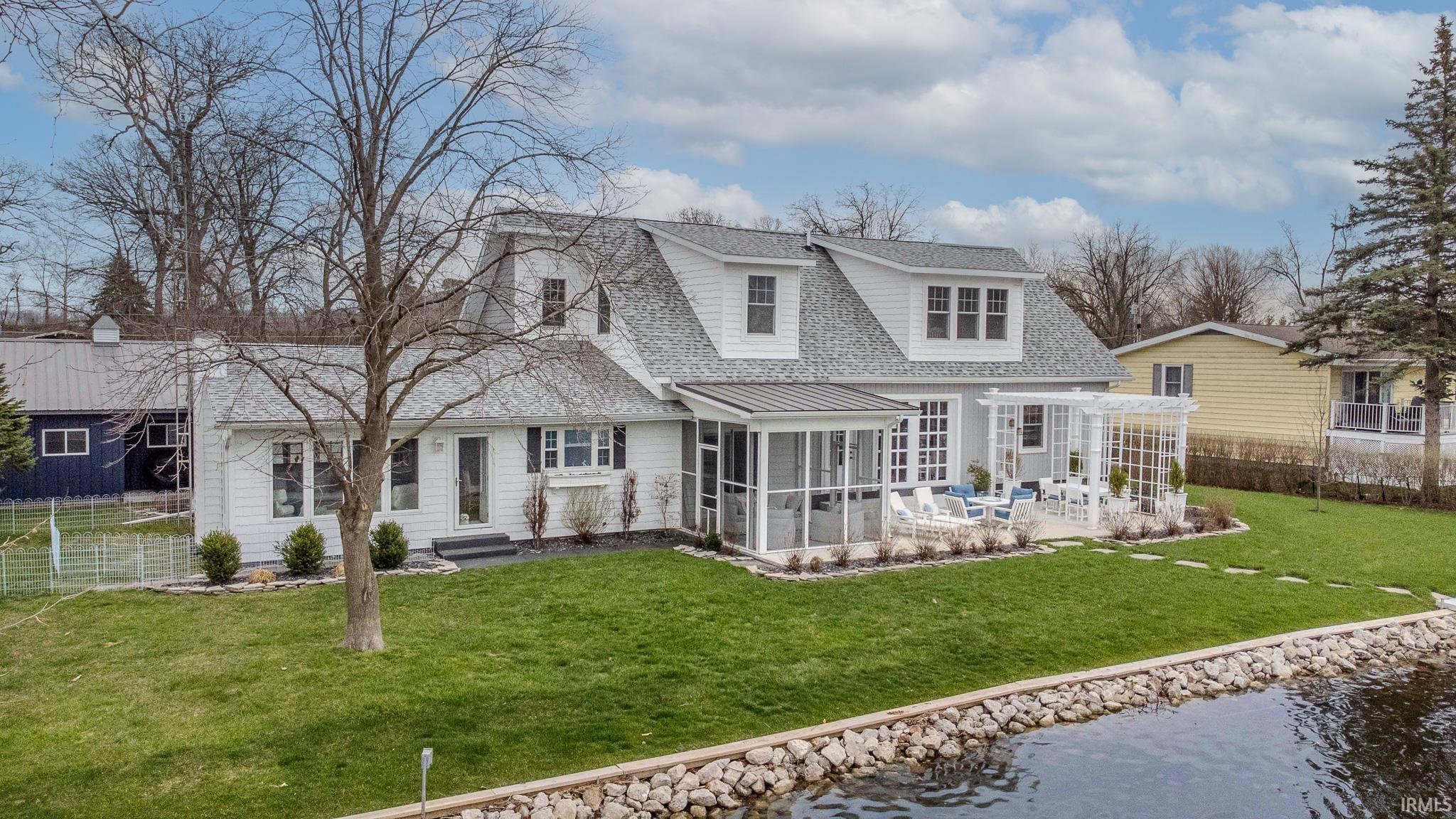 Image 1: Back of house with a sunroom, a shingled roof, and a water view, Back Of Structure Image 1: Back of house with a sunroom, a shingled roof, and a water view, Back Of Structure