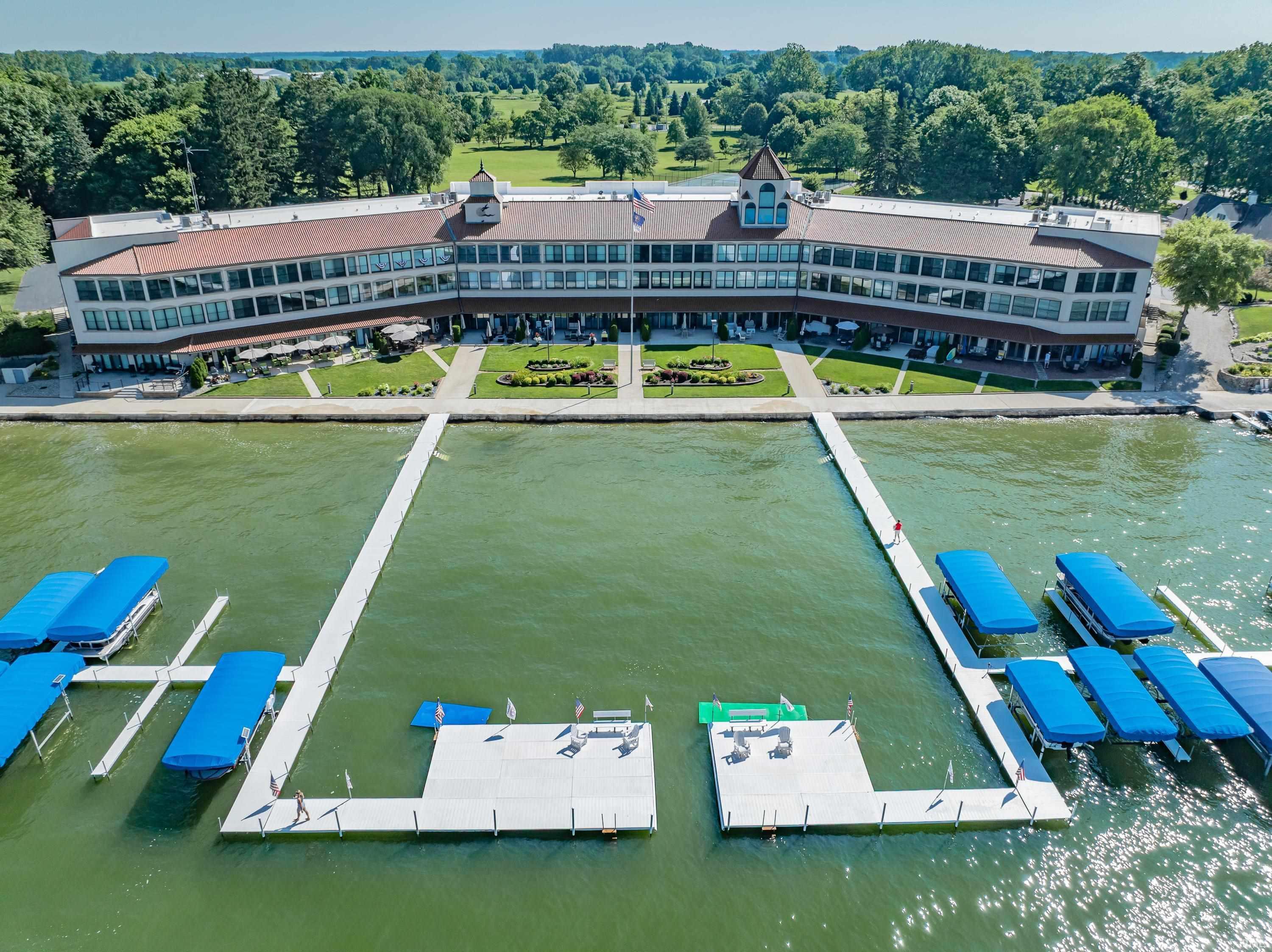 Image 0: Waterfront property featuring extensive private dockage with multiple boat slips, a large building with multiple balconies, and a meticulously landscaped terraced lawn, Aerial View