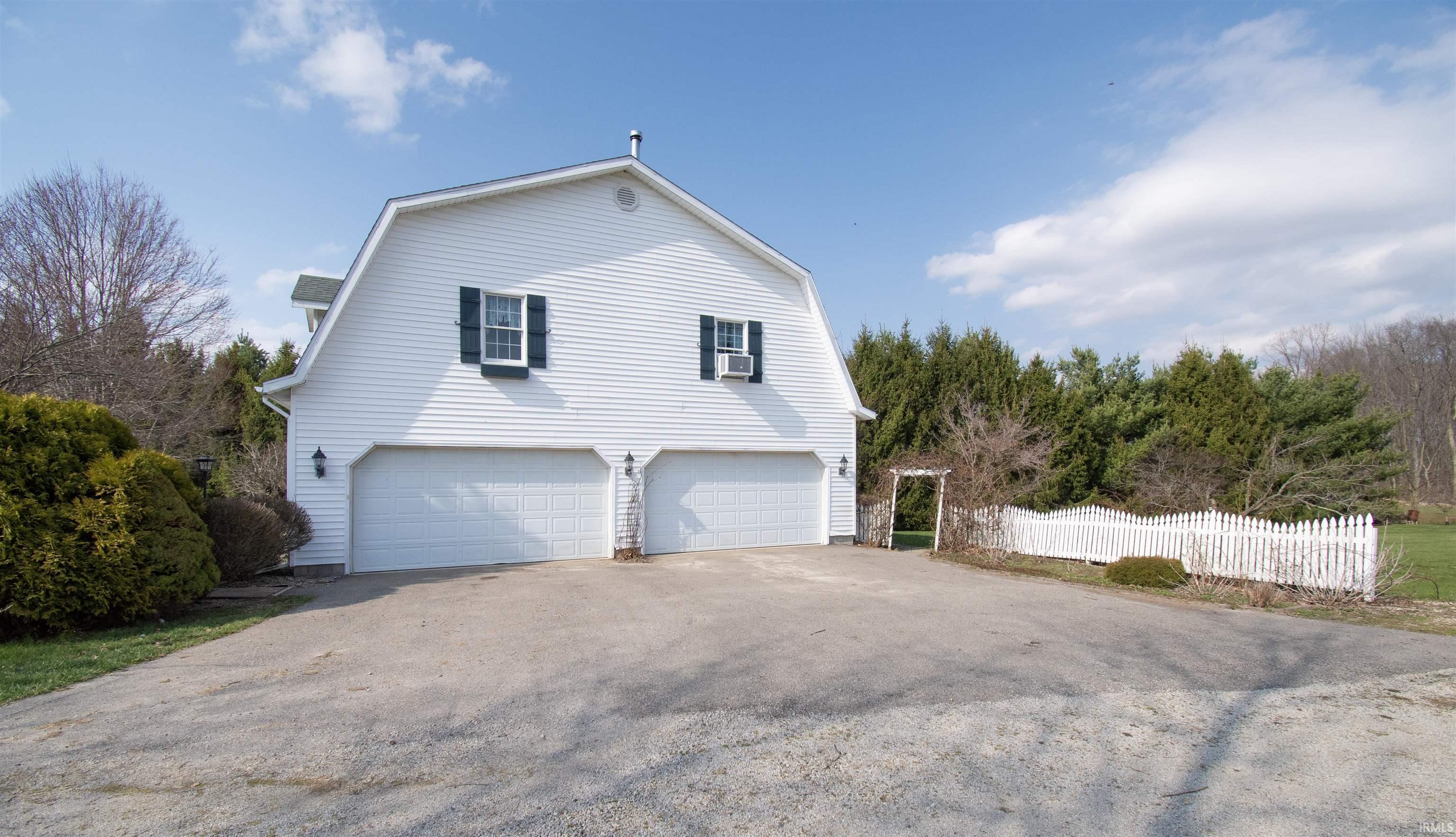 Image 2: View of side of property featuring a gambrel roof, asphalt driveway, and a garage, Side Of Structure