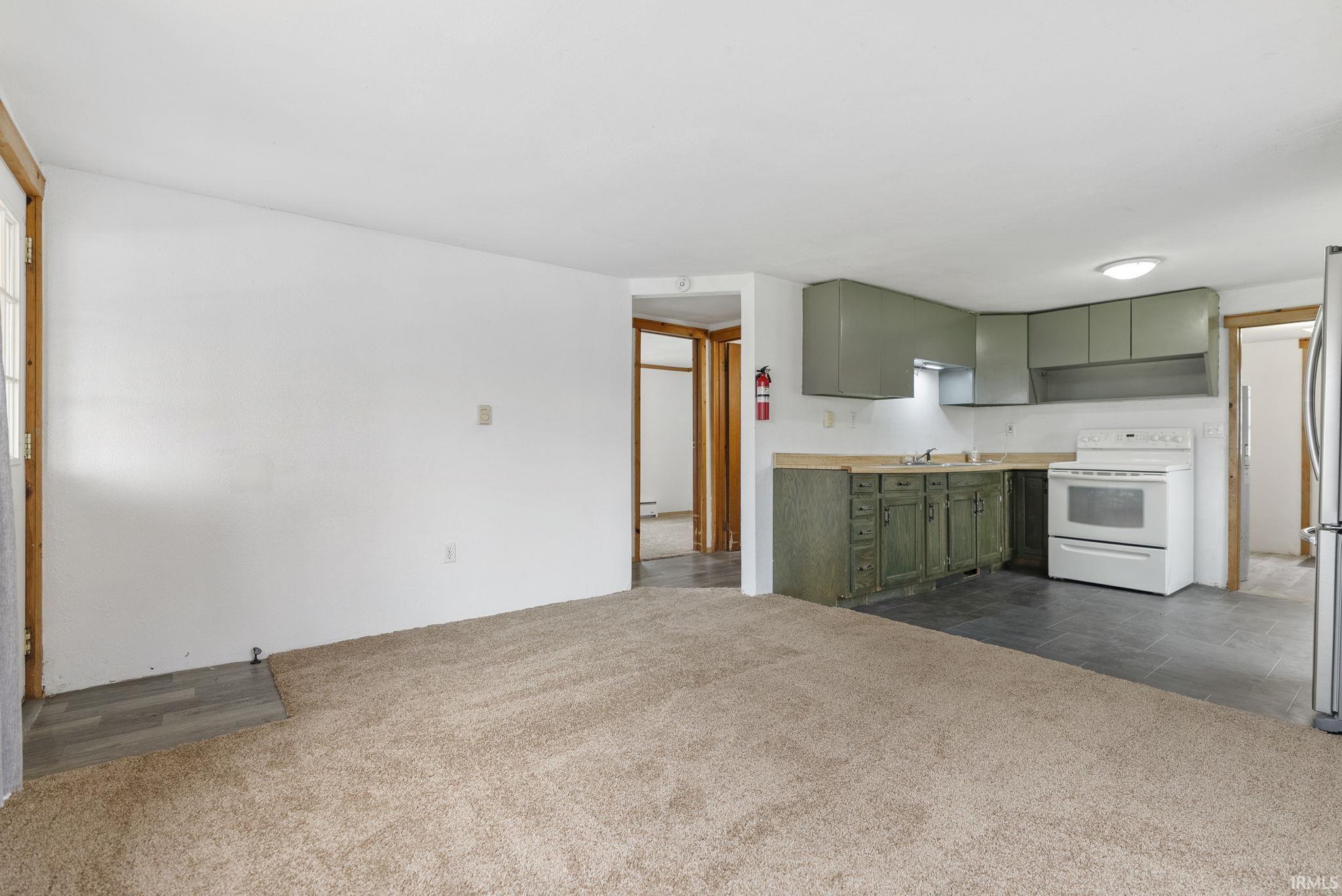 Image 3: Kitchen with green cabinets, white range with electric cooktop, light countertops, and dark colored carpet, Kitchen