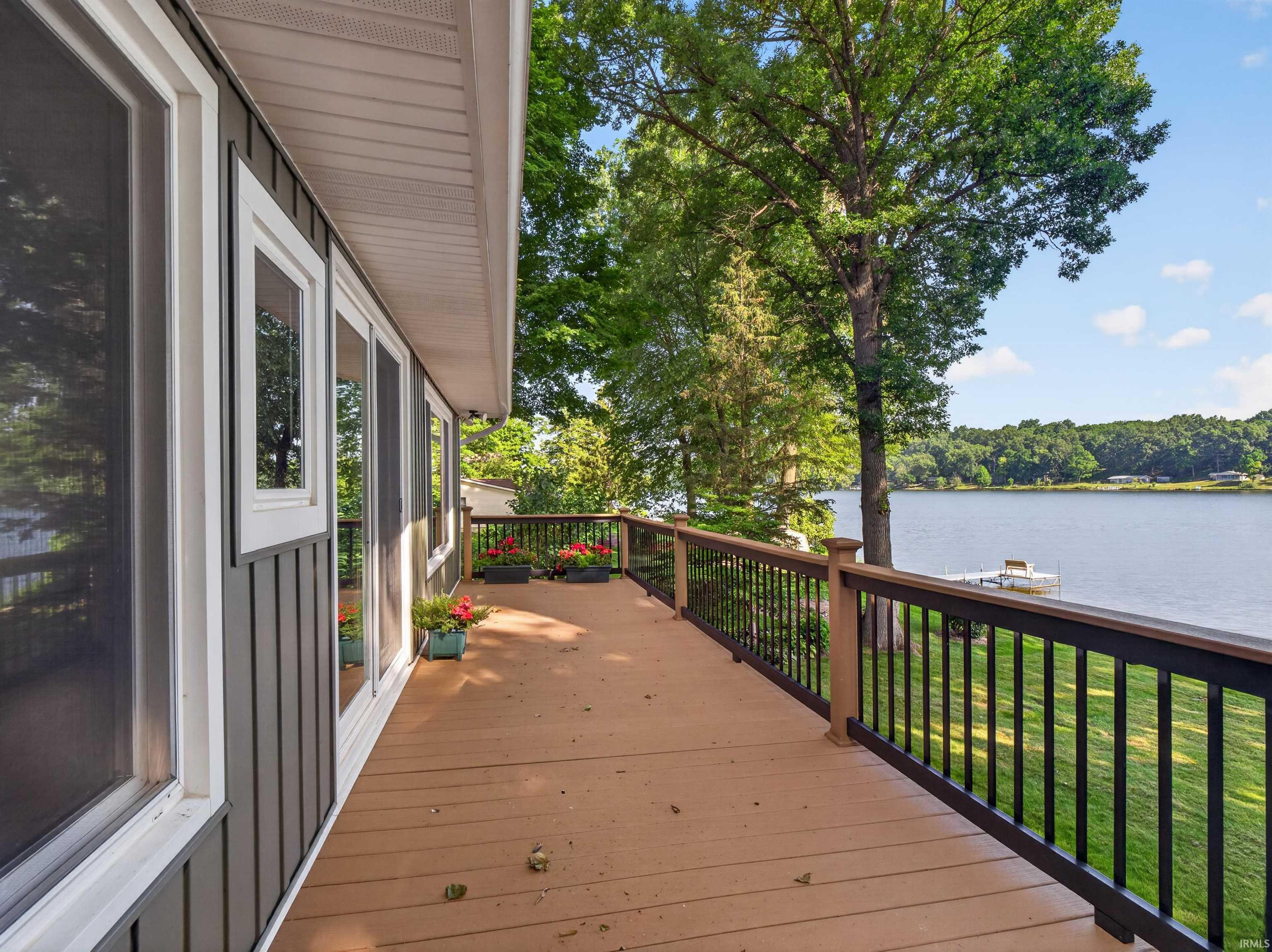 Image 3: Expansive outdoor deck featuring wood-finish flooring, a dark railing, and a serene lake backdrop, Deck Image 3: Expansive outdoor deck featuring wood-finish flooring, a dark railing, and a serene lake backdrop, Deck