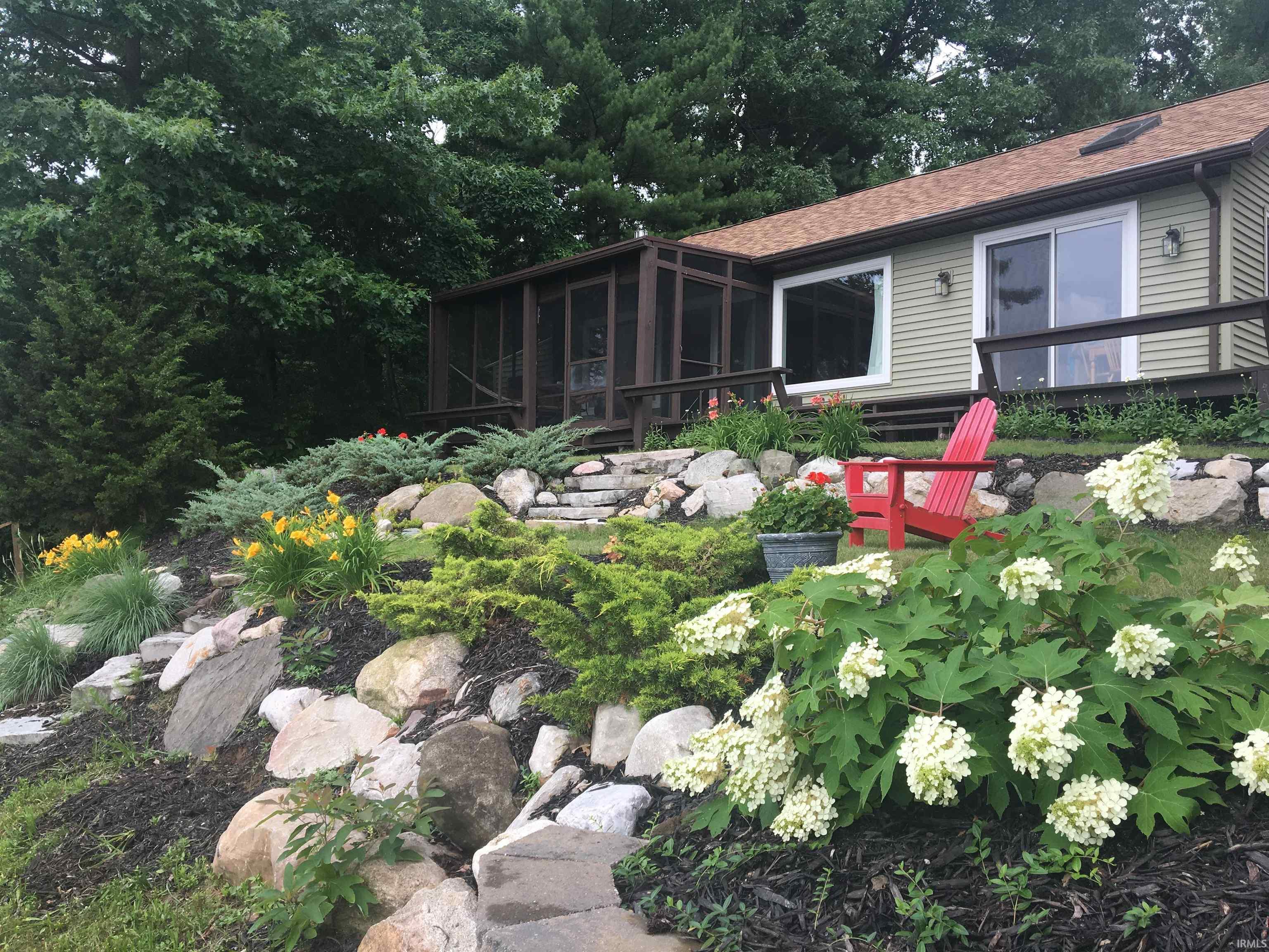 Image 1: Landscaped outdoor space featuring a stone pathway, diverse plantings, and a terraced rock garden, Back Of Structure Image 1: Landscaped outdoor space featuring a stone pathway, diverse plantings, and a terraced rock garden, Back Of Structure