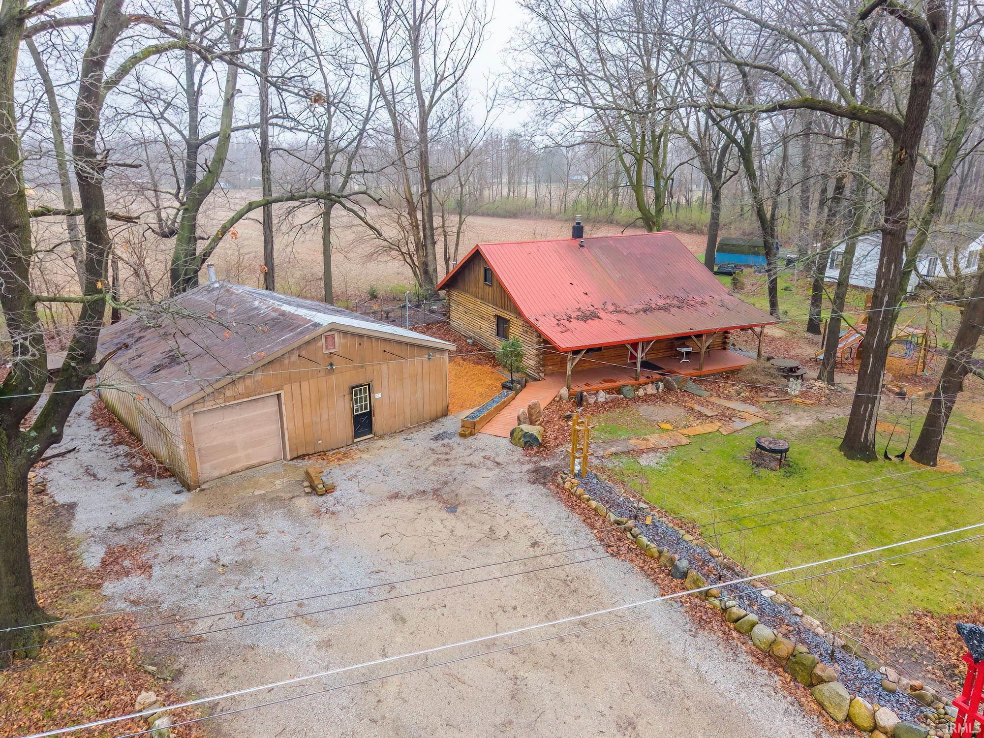 Image 1: View of front of property featuring a metal roof, a front lawn, driveway, and a detached garage, Front Of Structure Image 1: View of front of property featuring a metal roof, a front lawn, driveway, and a detached garage, Front Of Structure