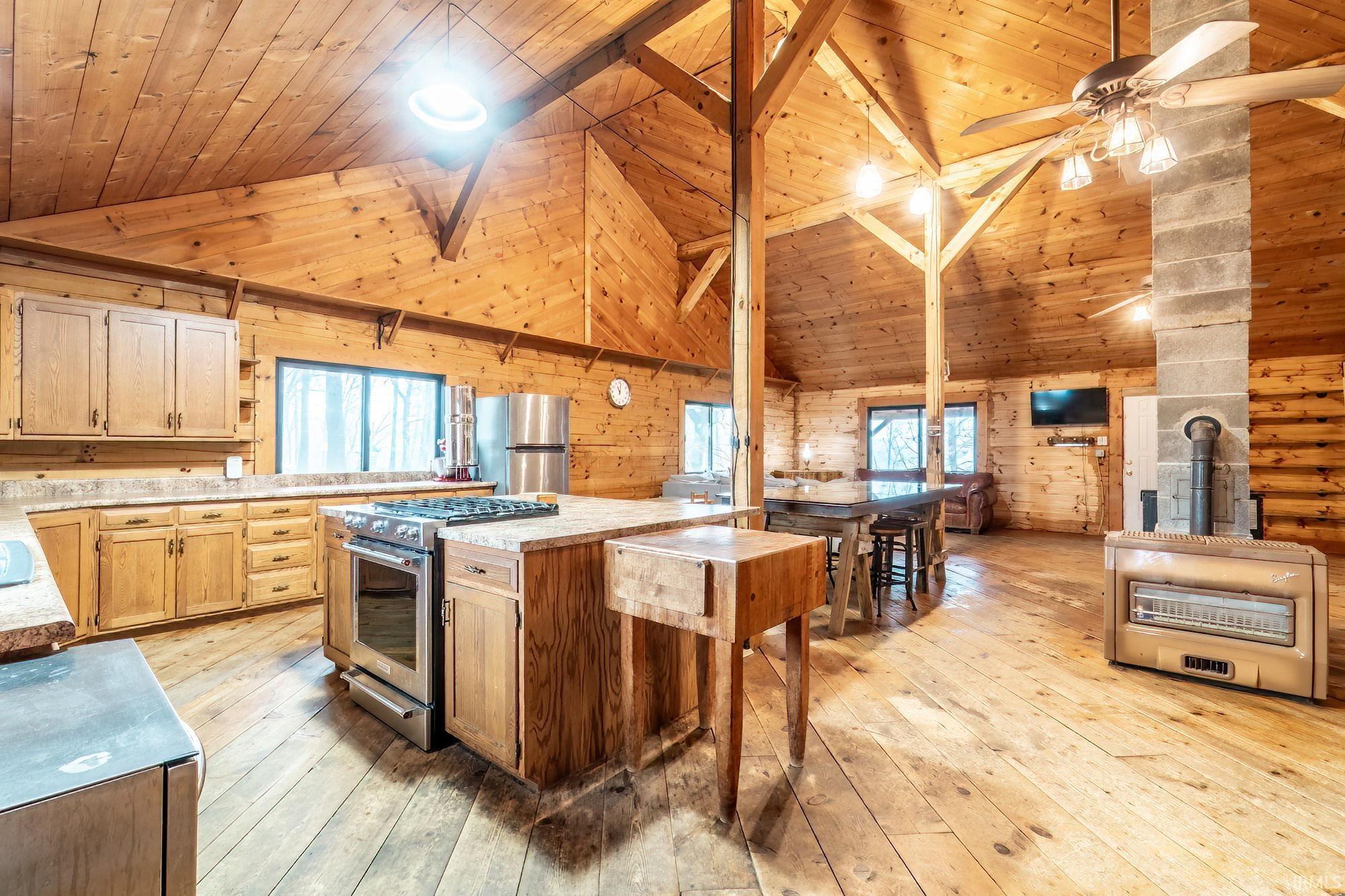 Image 2: Kitchen with wooden walls, a vaulted wooden ceiling, stainless steel appliances, light countertops, and light wood-style floors, Kitchen Image 2: Kitchen with wooden walls, a vaulted wooden ceiling, stainless steel appliances, light countertops, and light wood-style floors, Kitchen