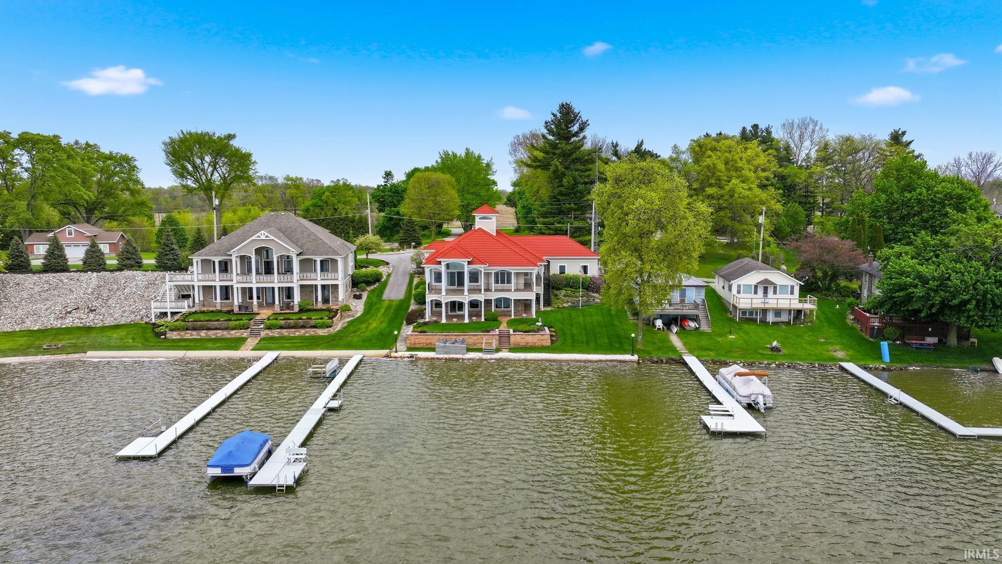 Image 3: Waterfront property featuring a private boat dock, green lawn, established landscaping, and mature trees, Aerial View